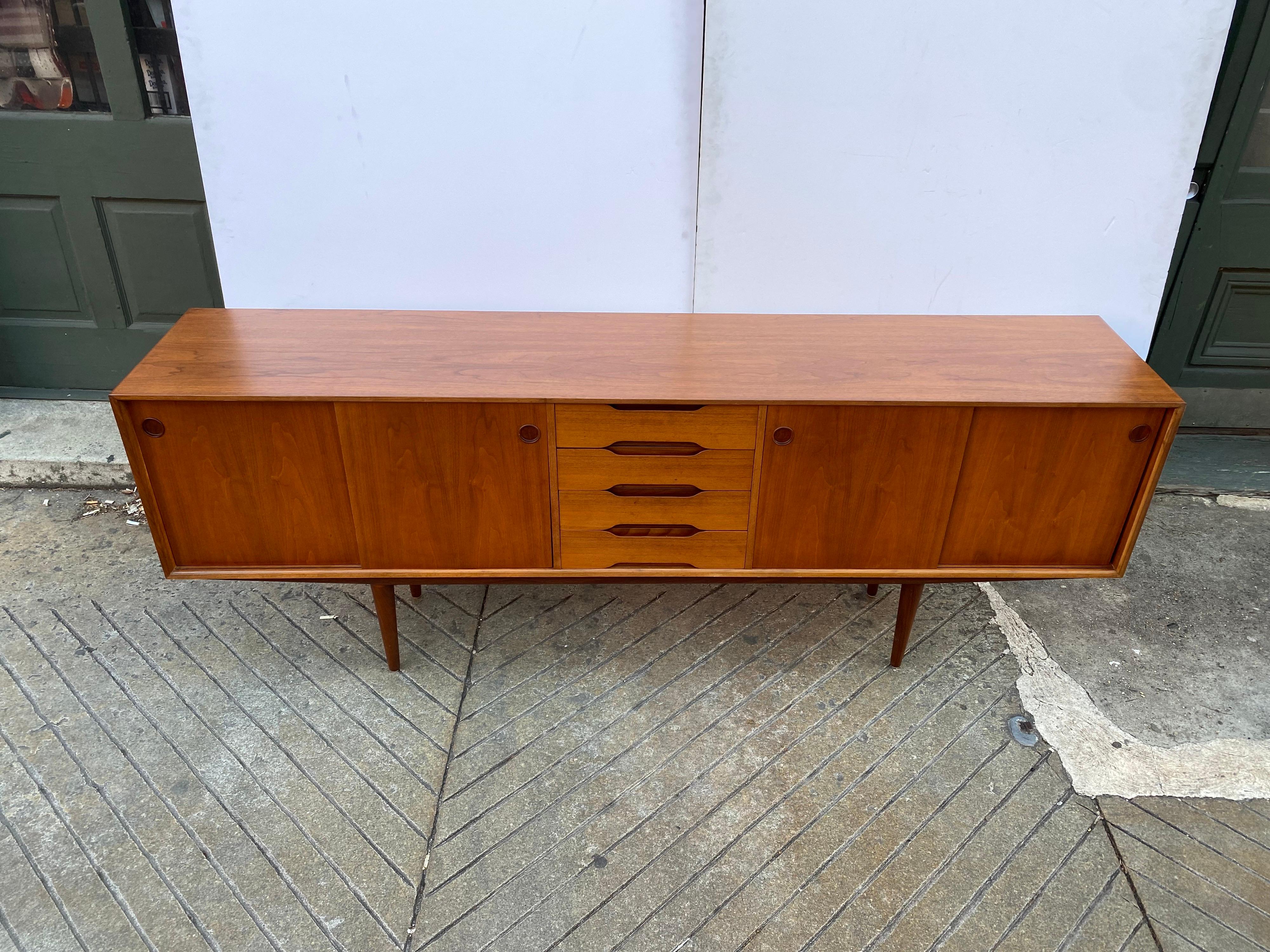 Fredrik Kayser for Gustav Bahus teak credenza. Newly refinished, beautiful grain throughout! Doors slide easily to reveal an adjustable shelf on the right side and open space on the left. Center is 4 pull out drawers with felt bottoms. Legs do