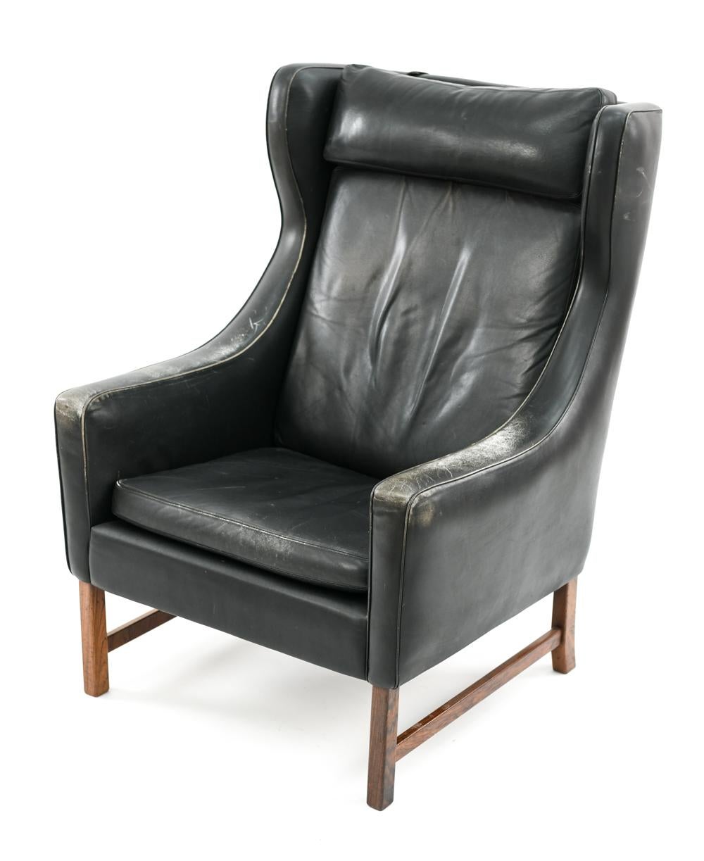 This midcentury wingback lounge chair was designed in 1964-1965 by Fredrik Kayser for Vatne Mobler, Norway. This model 965 chair features a rosewood base and black leather upholstered seat, back, and headrest cushions for ultimate comfort and style.