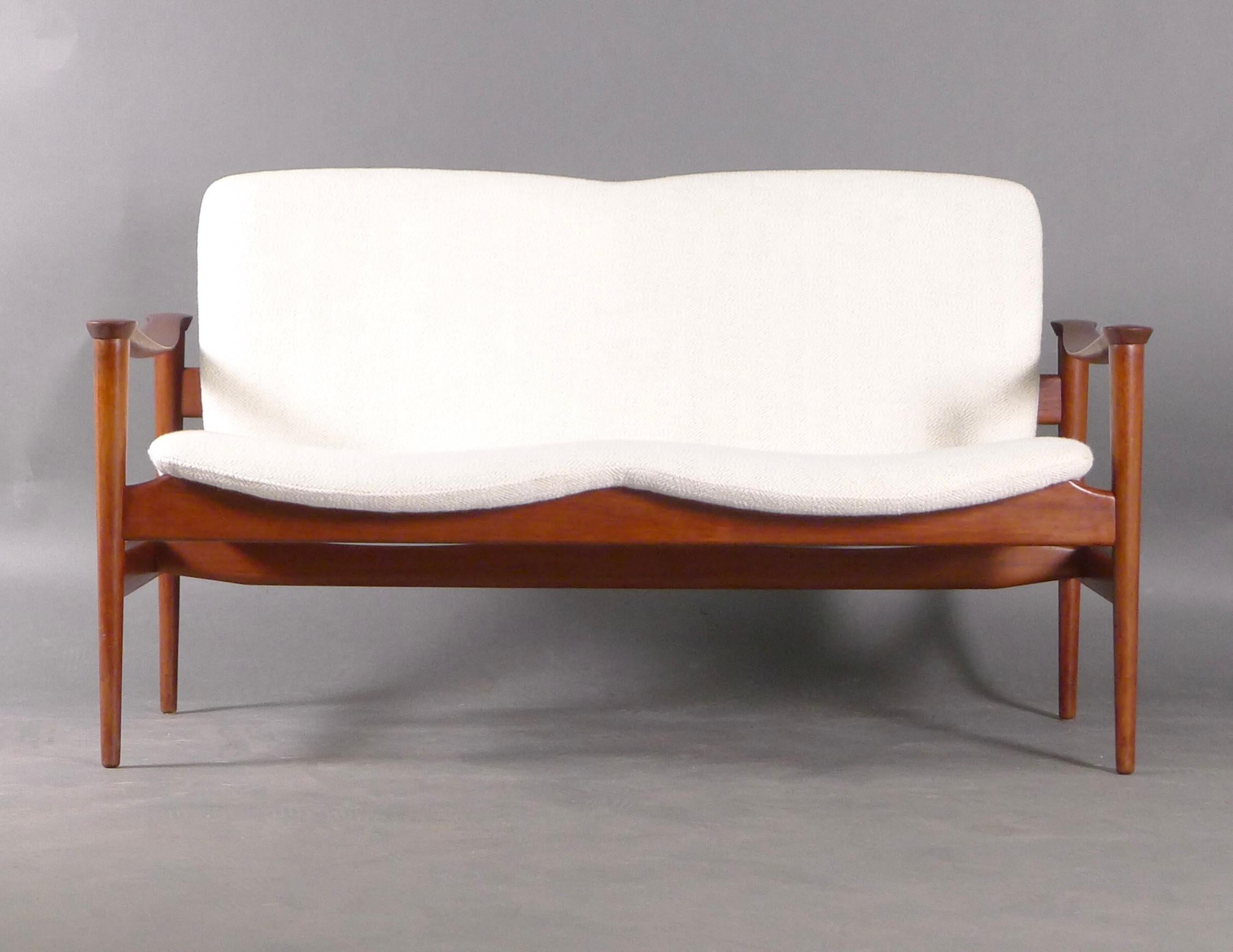 Beautiful Norwegian two-seater sofa or loveseat, model 711, designed by Fredrik A Kayser in 1960 and made by Vatne Lenestolfabrikk.  The teak frame has a lovely patina and features roundels to the shaped armrests.  The sofa has been newly