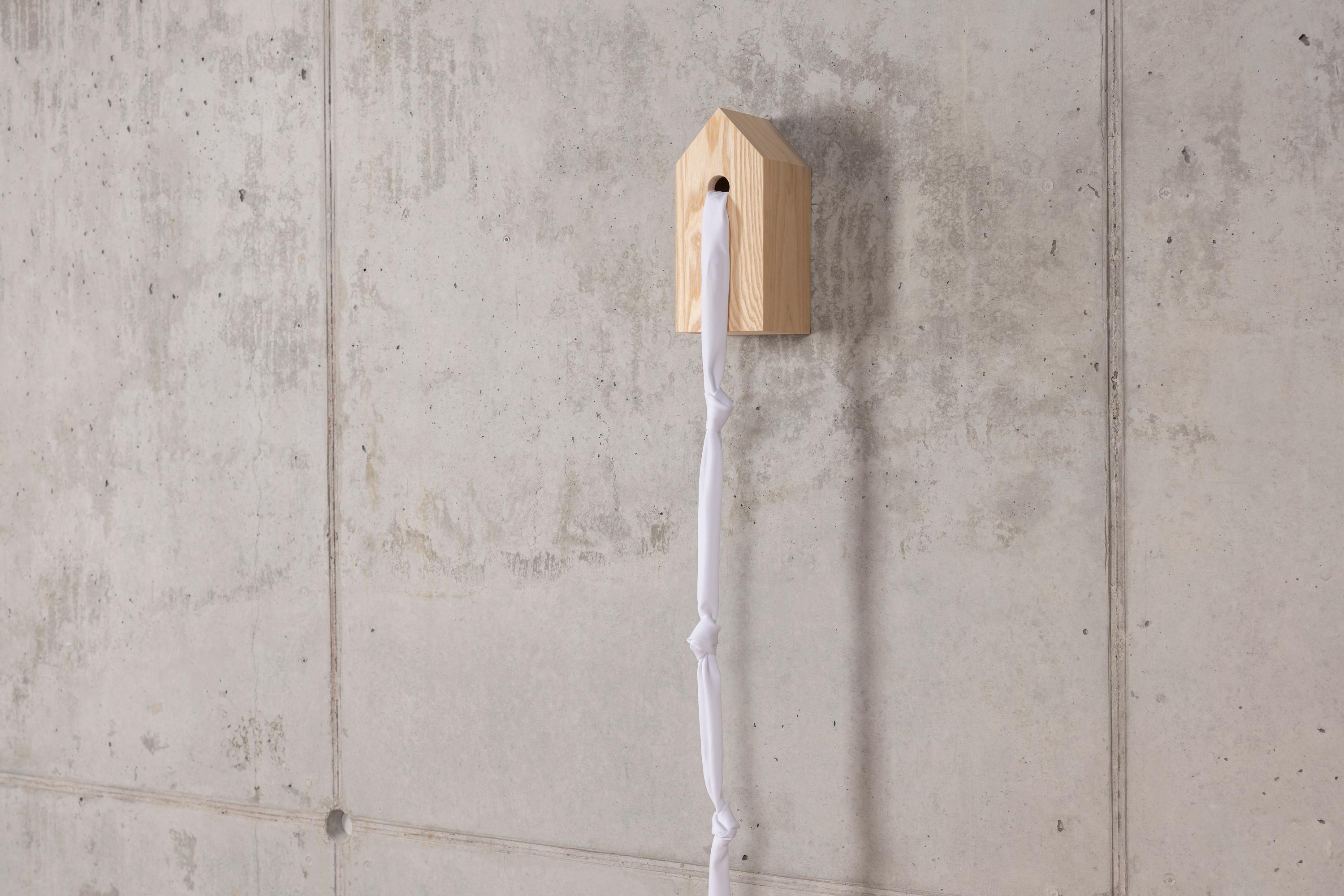 Free as a bird. Escapism at its finest.

This artwork is a birdhouse which has knotted white sheets hanging from them. The birdhouse is handmade from ashwood and has a mounting system designed into the wood, on the back. De knotted white sheets are