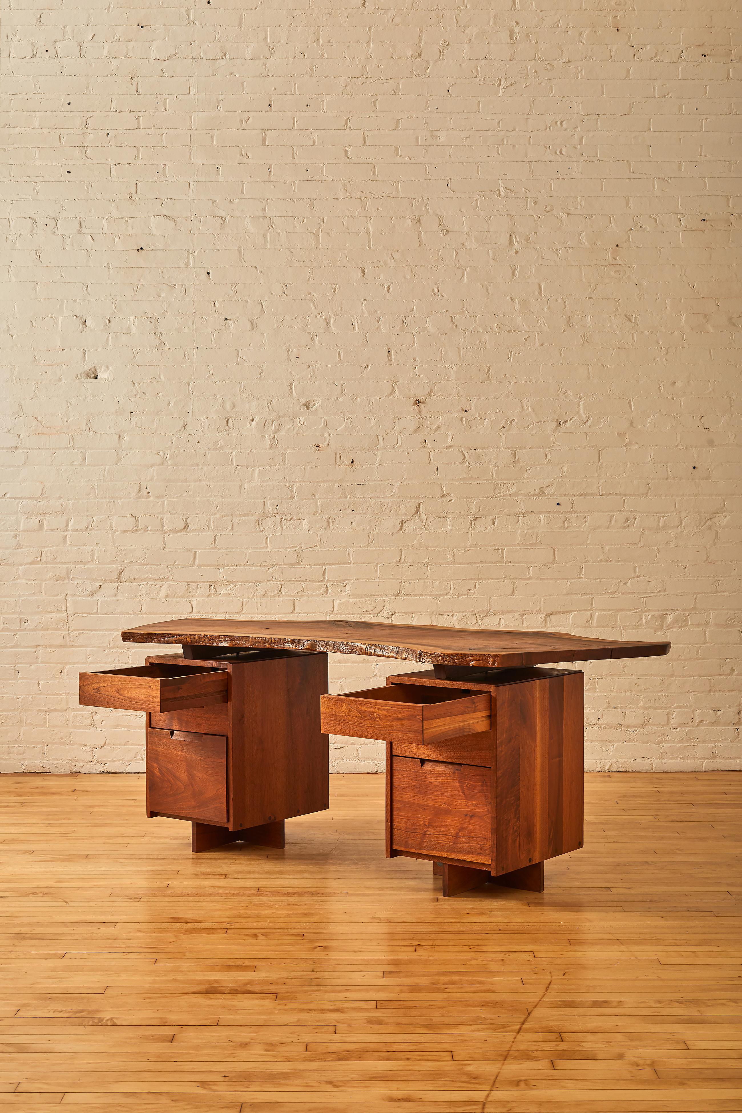 Free-edge double pedestal desk by George Nakashima in walnut with butterfly joinery on desk top. 

