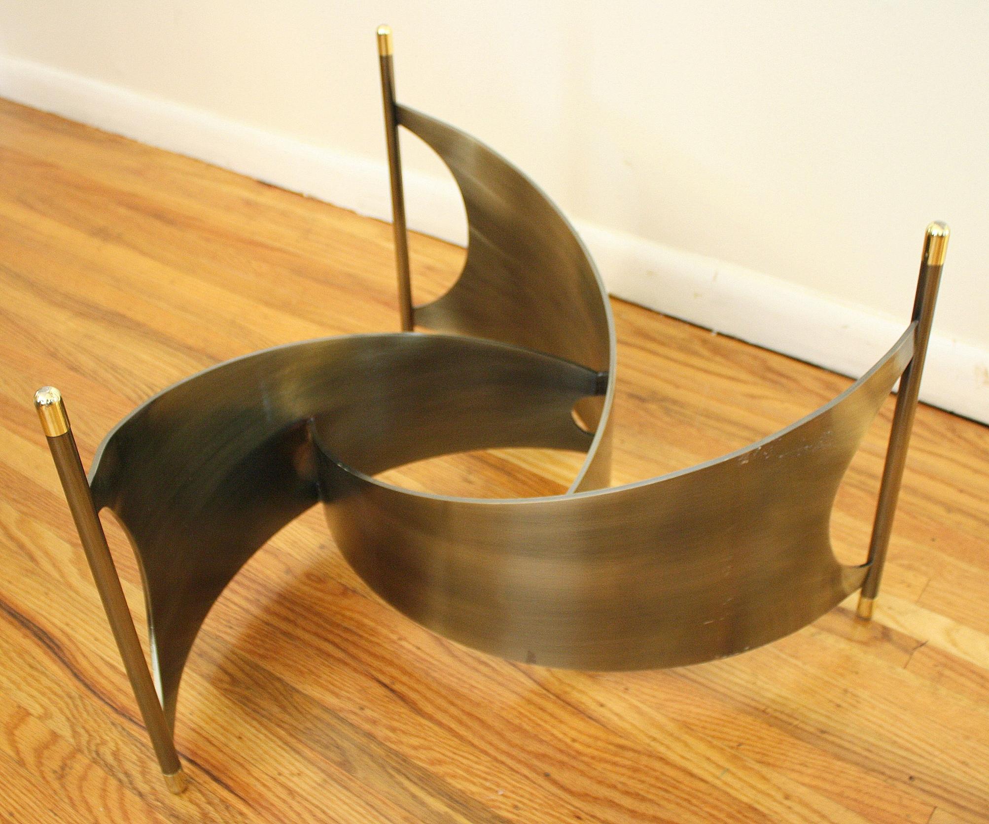 This is a Mid-Century Modern propeller style coffee table. It has a free form glass top and the base has a sleek polished metal base. Reminiscent of the sea, this table is a beautiful combination of oceanic and nautical themes.