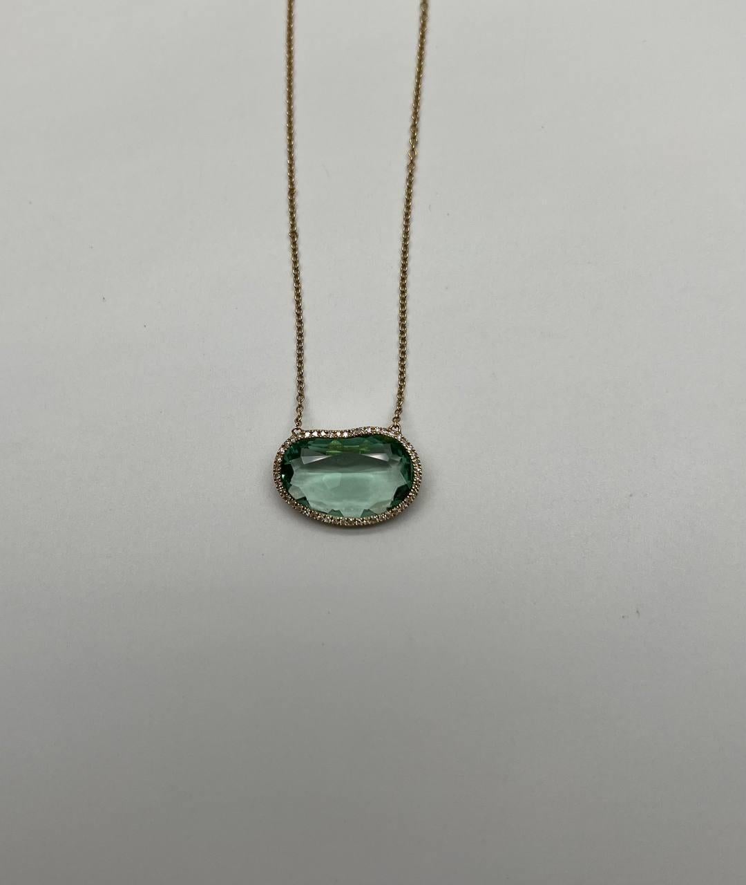 This elegant pendant necklace features a smooth, translucent light green tourmaline in faceted free form cut & shape. The stone is set in a minimalist diamond halo, allowing light to enhance its natural beauty. 14K yellow gold. 

The pendant is
