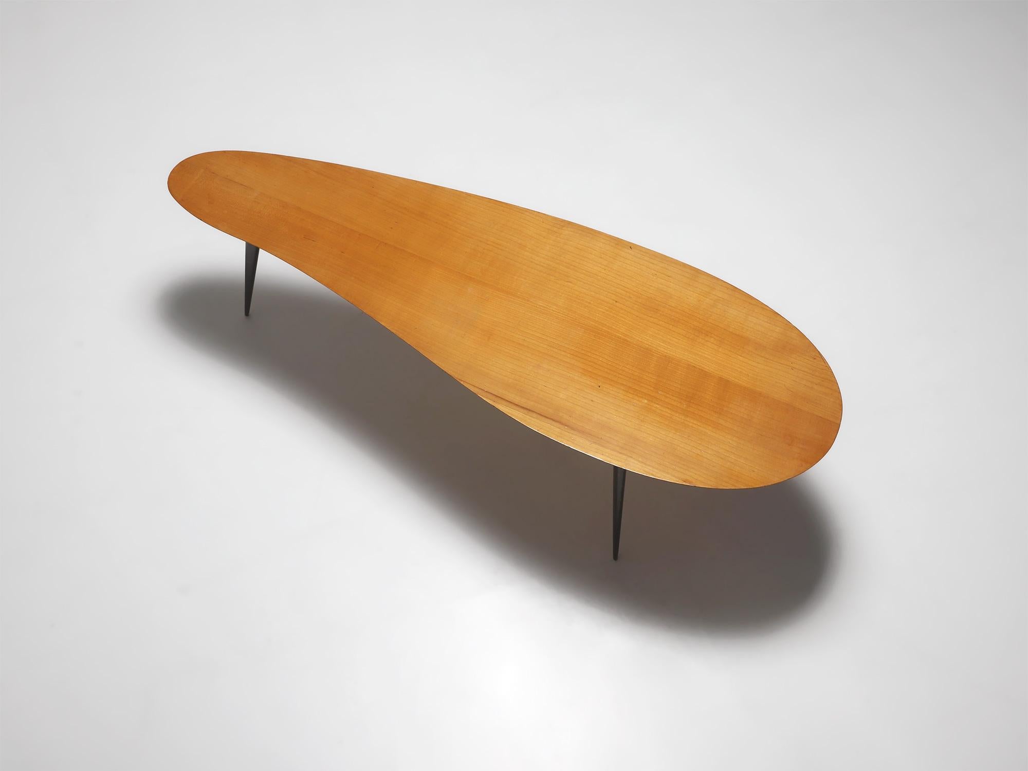 Beautiful handcrafted kidney shaped coffee table made in the 1950s. This elegant mid century coffee table has three solid triangular wood legs and is made in pear wood, a strong but light wood with a honey colored look. The shape is perfect for use