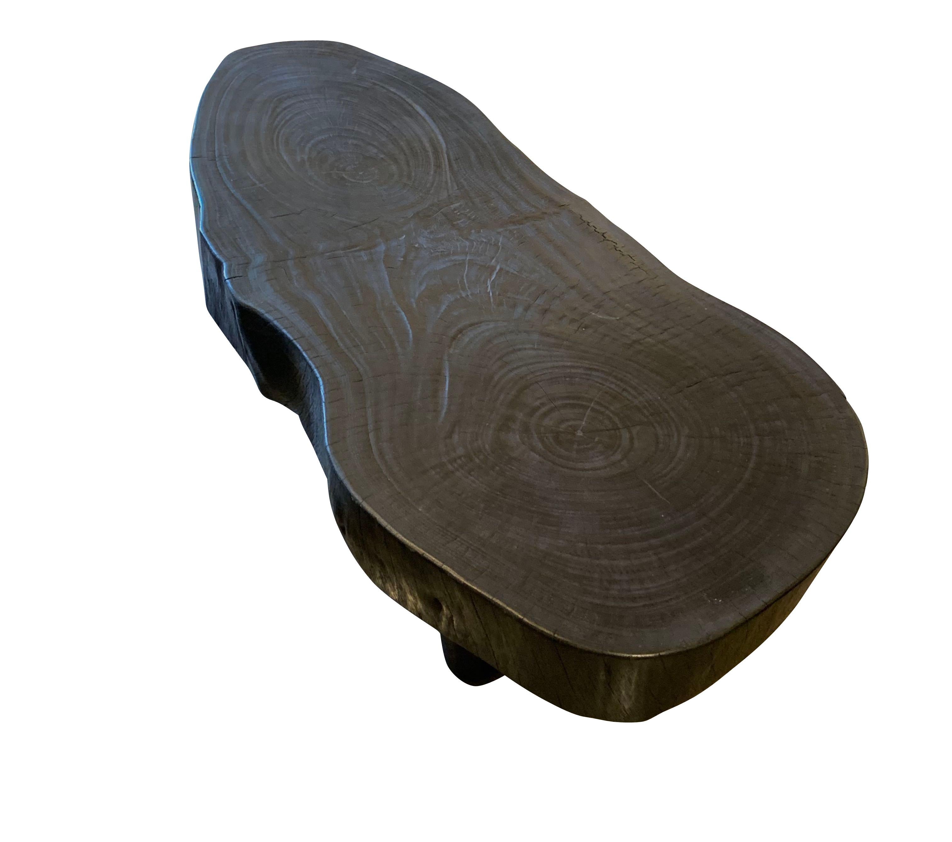 Indonesian freeform coffee table made from Suar wood that has been charred to give an ebonized appearance.
Circular rings are visible at each end of the top.
Suar wood is known to be very durable.
Clearance space under the table is 10