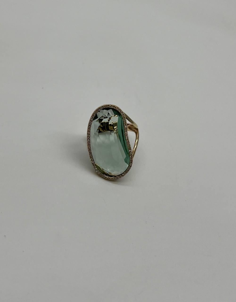 This striking ring showcases a captivating free form green amethyst prasiolite, elegantly framed by a halo of shimmering diamonds. The central stone, with a primary carat weight of 16.26, exudes a soft, ethereal glow.

Crafted in 14k gold, the band