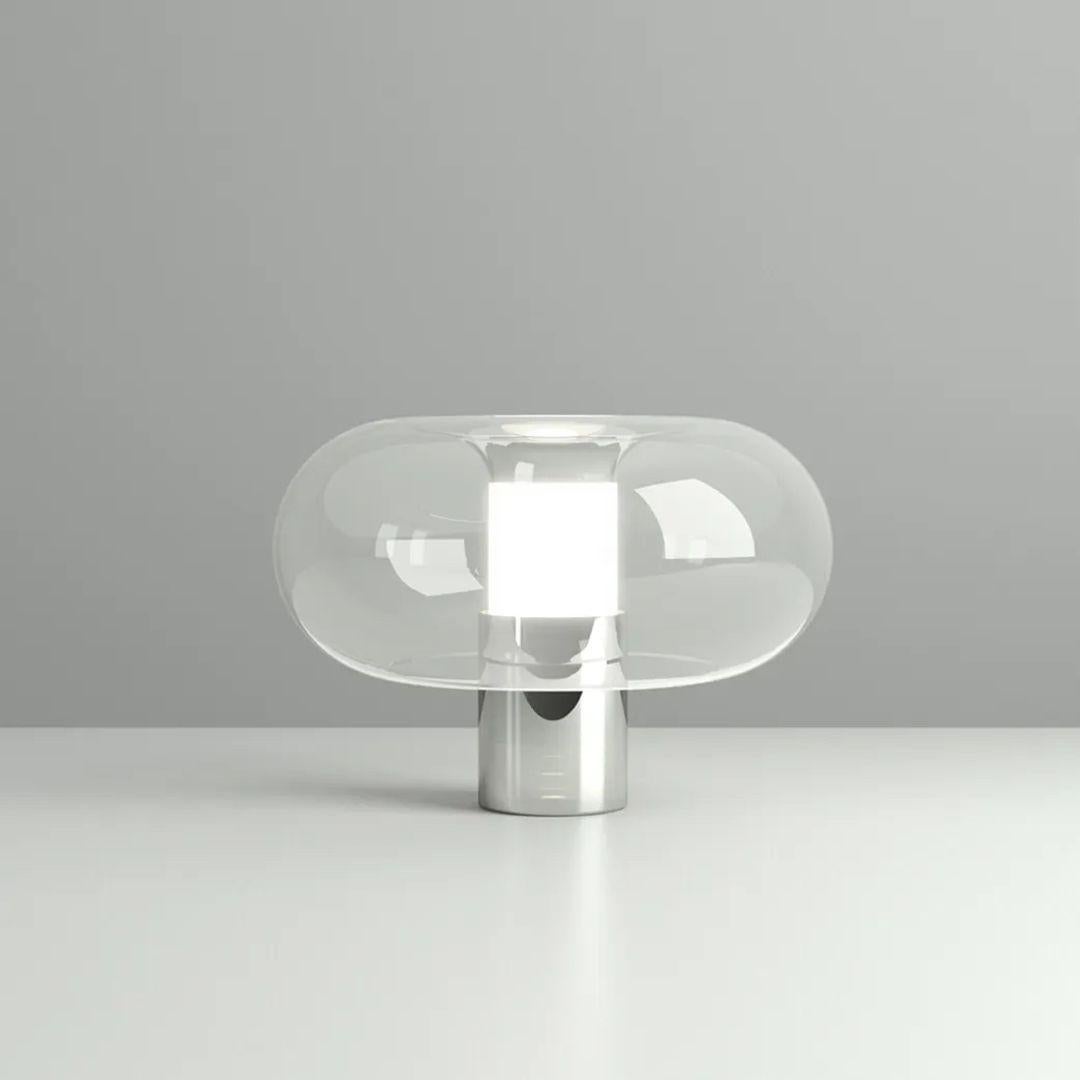 La lampe à poser Fontanella de FontanaArte présente un artisanat italien personnalisé, mettant en valeur l'art lumineux. Conçu par Federico Peri, ce chef-d'œuvre contemporain marie un abat-jour arrondi en verre cristallin à une structure centrale