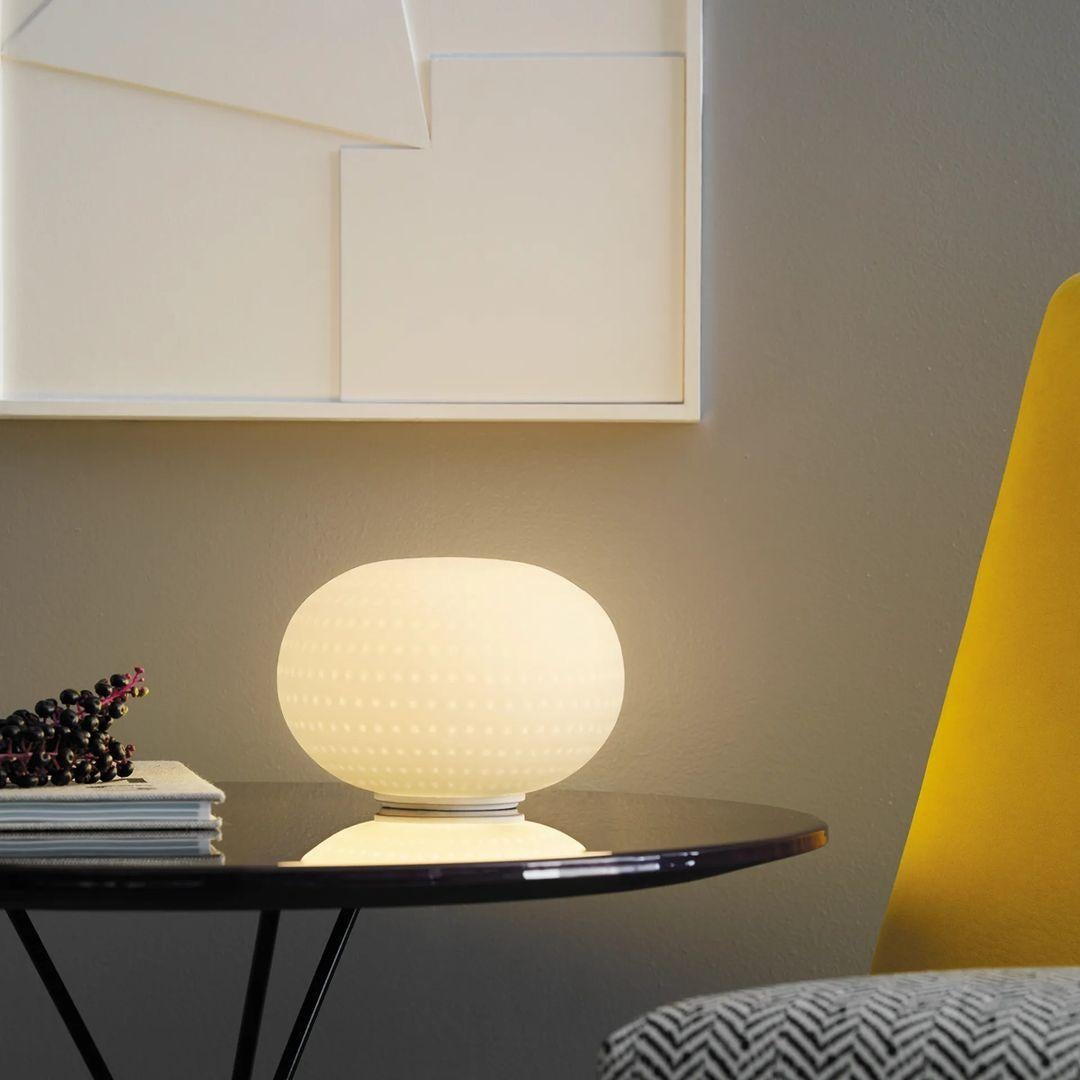 Bianca is a family of luminaires with the decoration on the diffuser surface features an orderly series of shallow delicate grooves etched into the white glass, yielding an effect resembling small footprints on fresh snow. Mouth blown, belt sanded