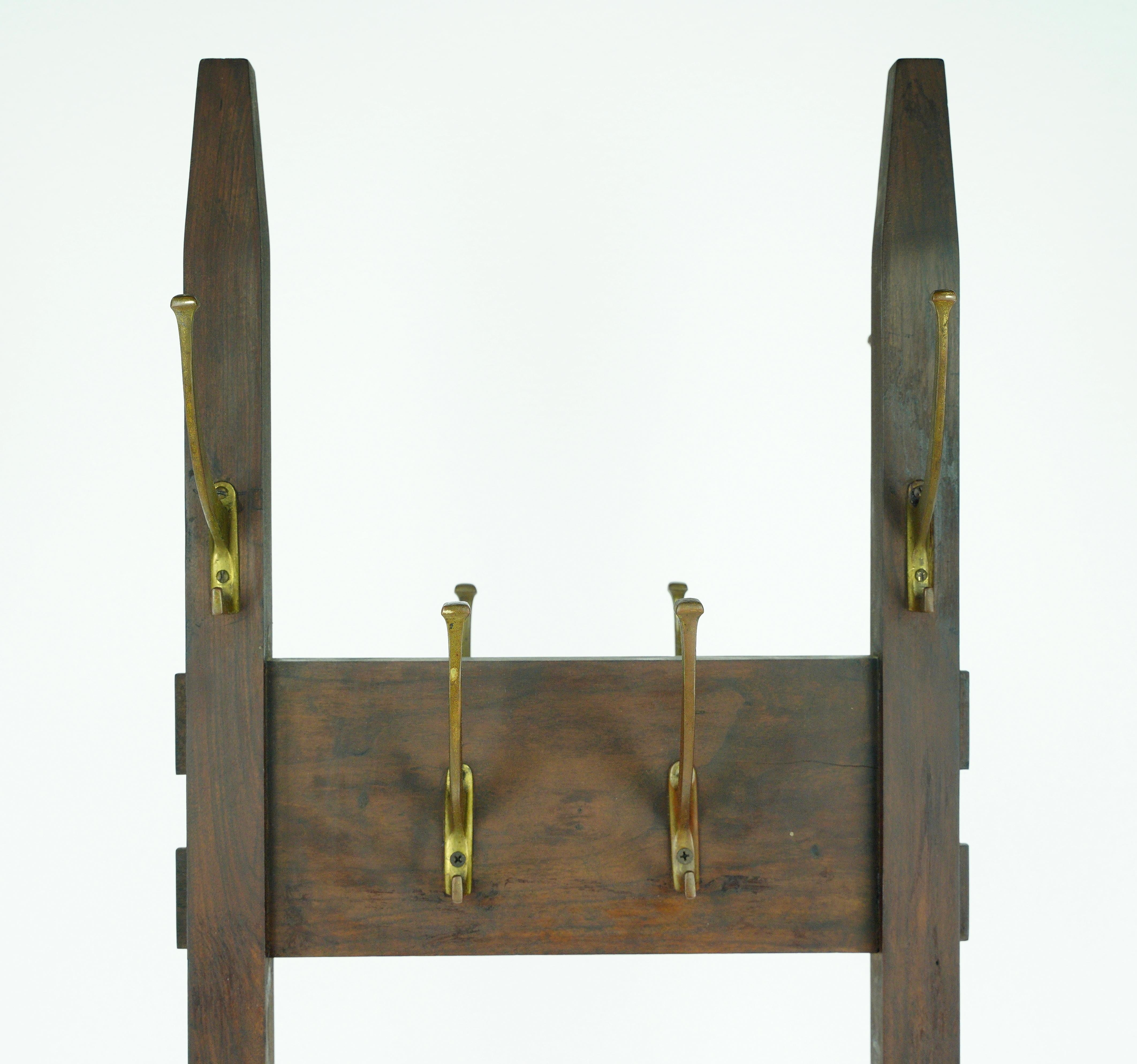 This free standing coat rack echoes timeless design. With an Arts & Crafts style and brass finished steel hooks, it embodies both form and function. This coat rack adds a touch of vintage charm to spaces, providing a convenient storage solution for