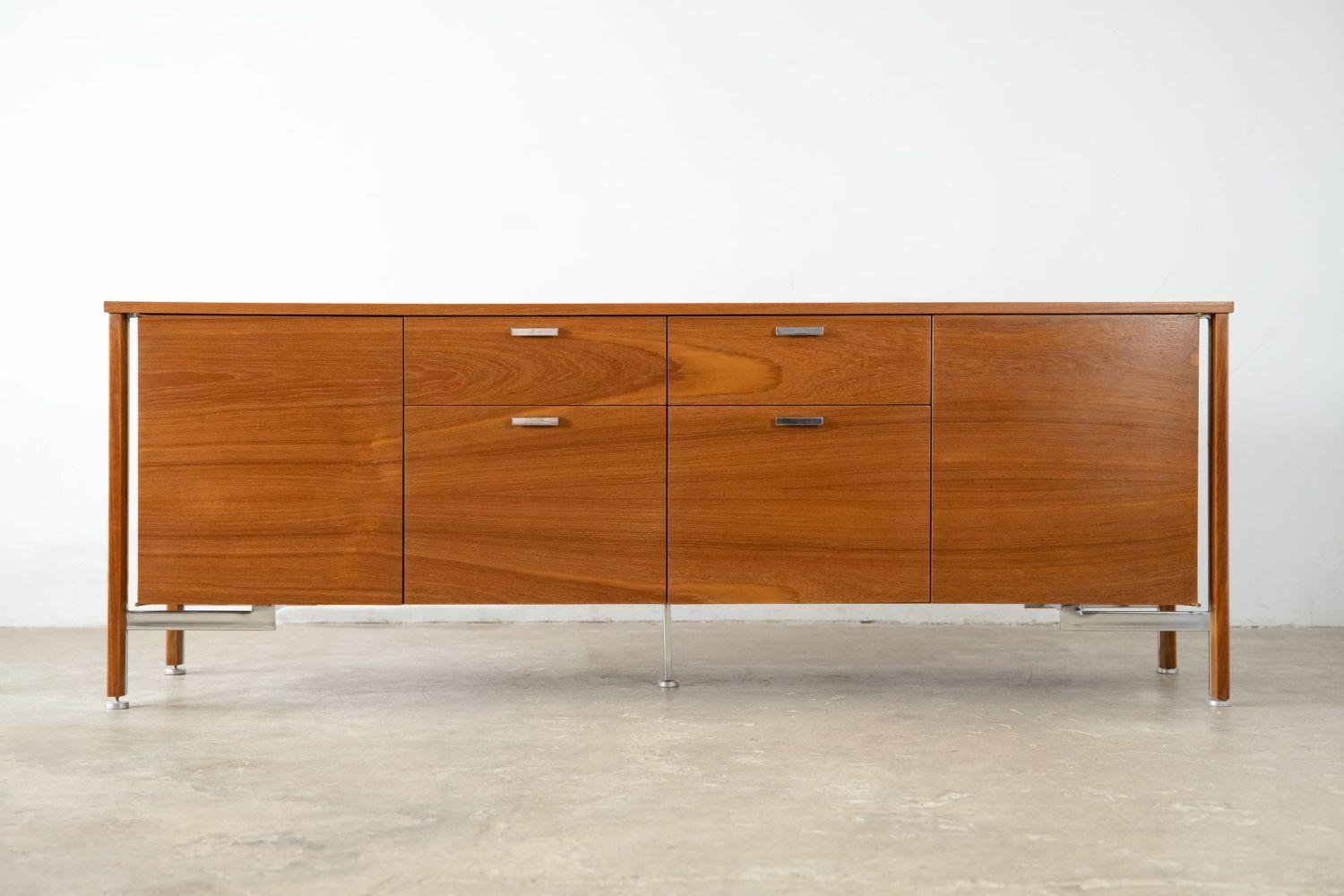 Beautiful free-standing credenza by Robert John, 1960s. The credenza has been professionally restored and is constructed from walnut with oak interior drawers, and sits on a polished stainless base with adjustable glides. The side compartments open