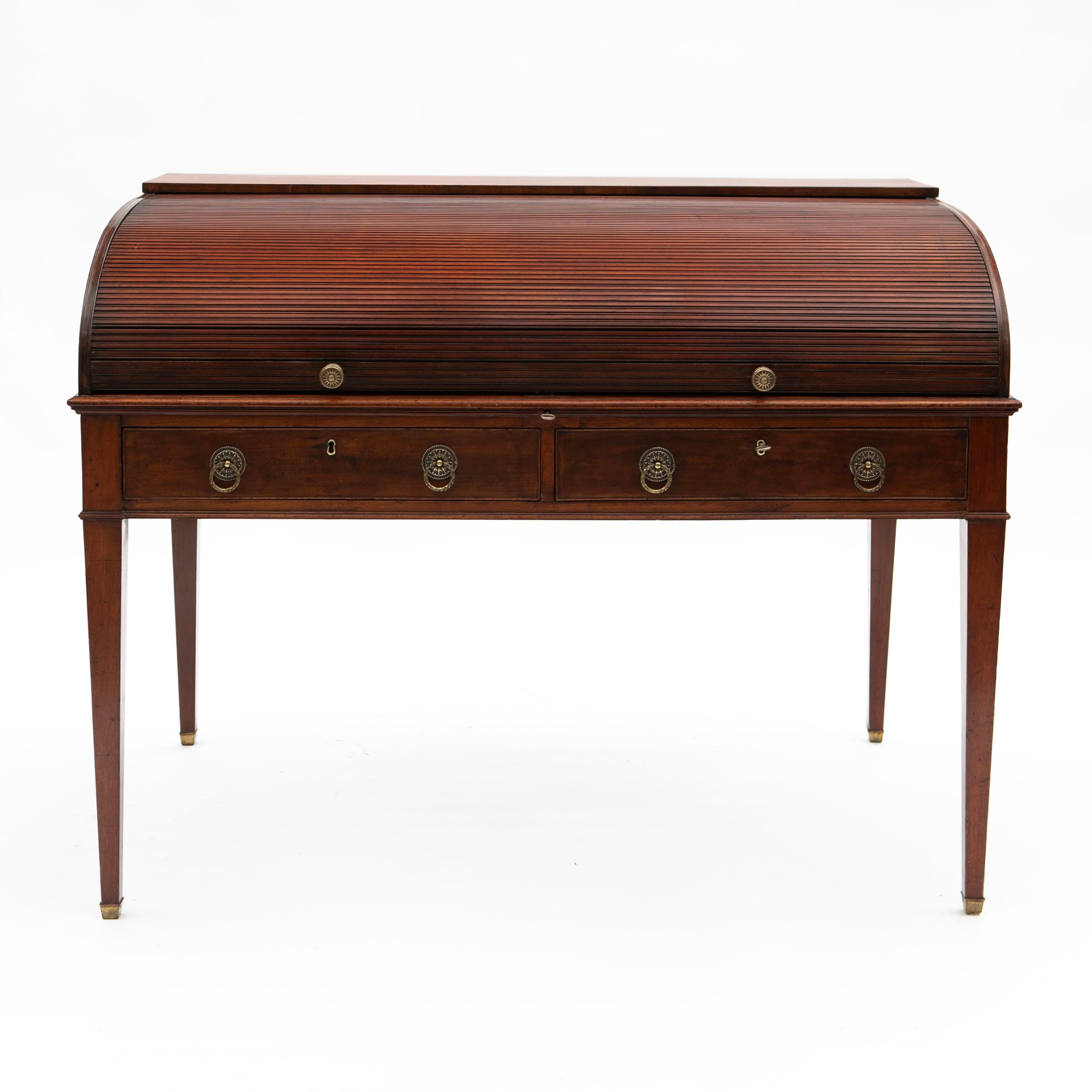 An elegant 19th century freestanding mahogany roll top writing desk.

Tambour top rolls back to reveal a fitted interior with drawers, pigeon holes and a slant lid leather writing surface. Apron with 2 larger drawers raised on elegant square tapered