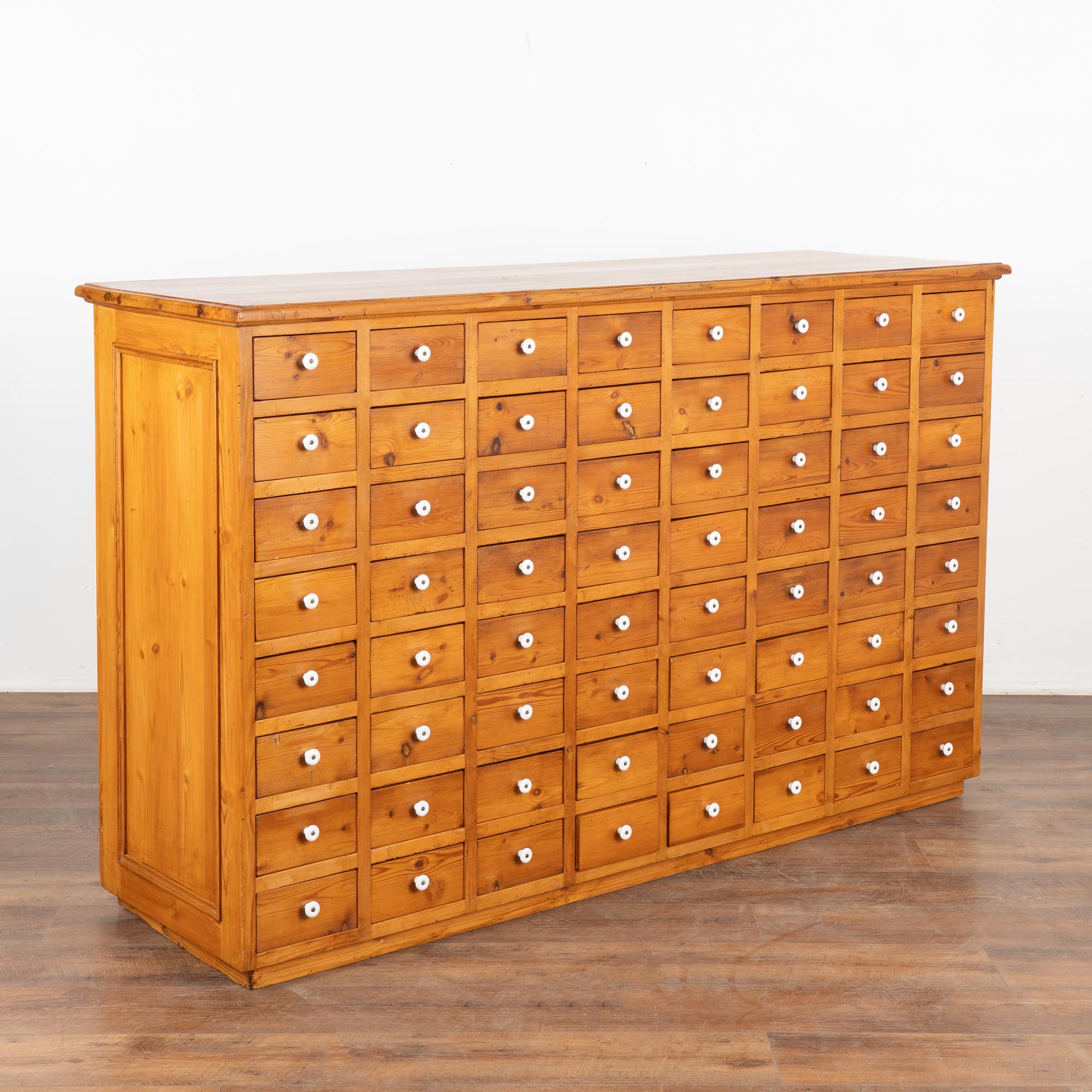 Fun and function abound in this free standing pine apothecary with 64 drawers. This delightful apothecary originally served as a shop counter or storage cabinet. Counters similar to this were used throughout shops in the European during the 1800's,