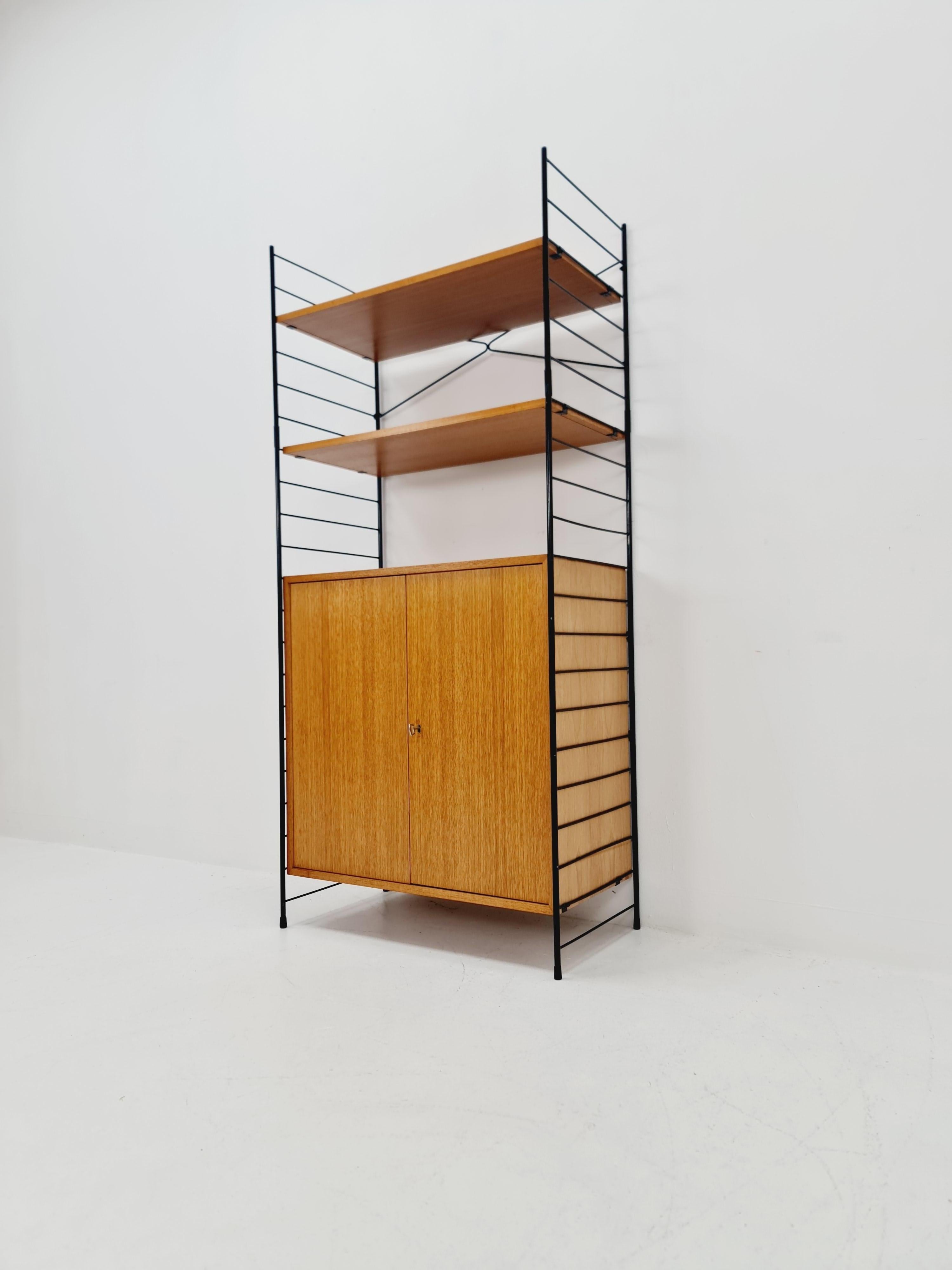 Sistema di scaffali String free standing, libreria con mobile  Eshe di WHB Germany, anni '50

Il sistema da scaffale è in ottime condizioni vintage. 

Misure:
Altezza: 159  cm
Larghezza: 72 cm 
Profondità: 39 cm 

Si prega di richiedere i prezzi per