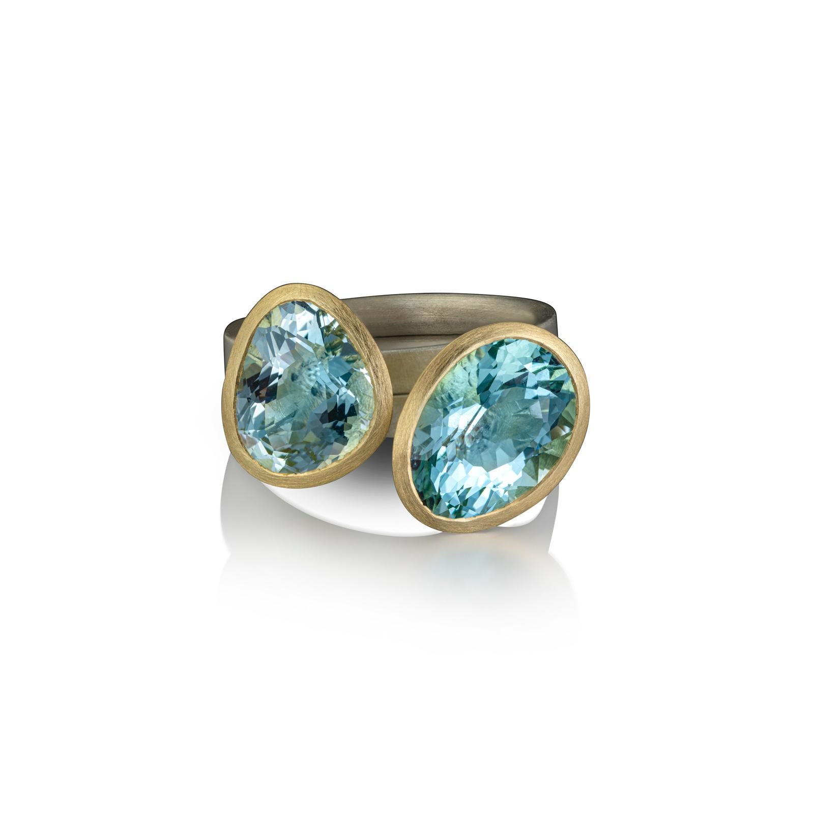 Clear bright blue freeform aquamarines, faceted in Mark’s signature ‘pebble’ shape. The gemstones are set in 18ct yellow gold on an inverted D silver band.

Item Details
- 18ct Yellow Gold, Silver band
- Freeform aquamarines 3.50cts and 3.75cts
-