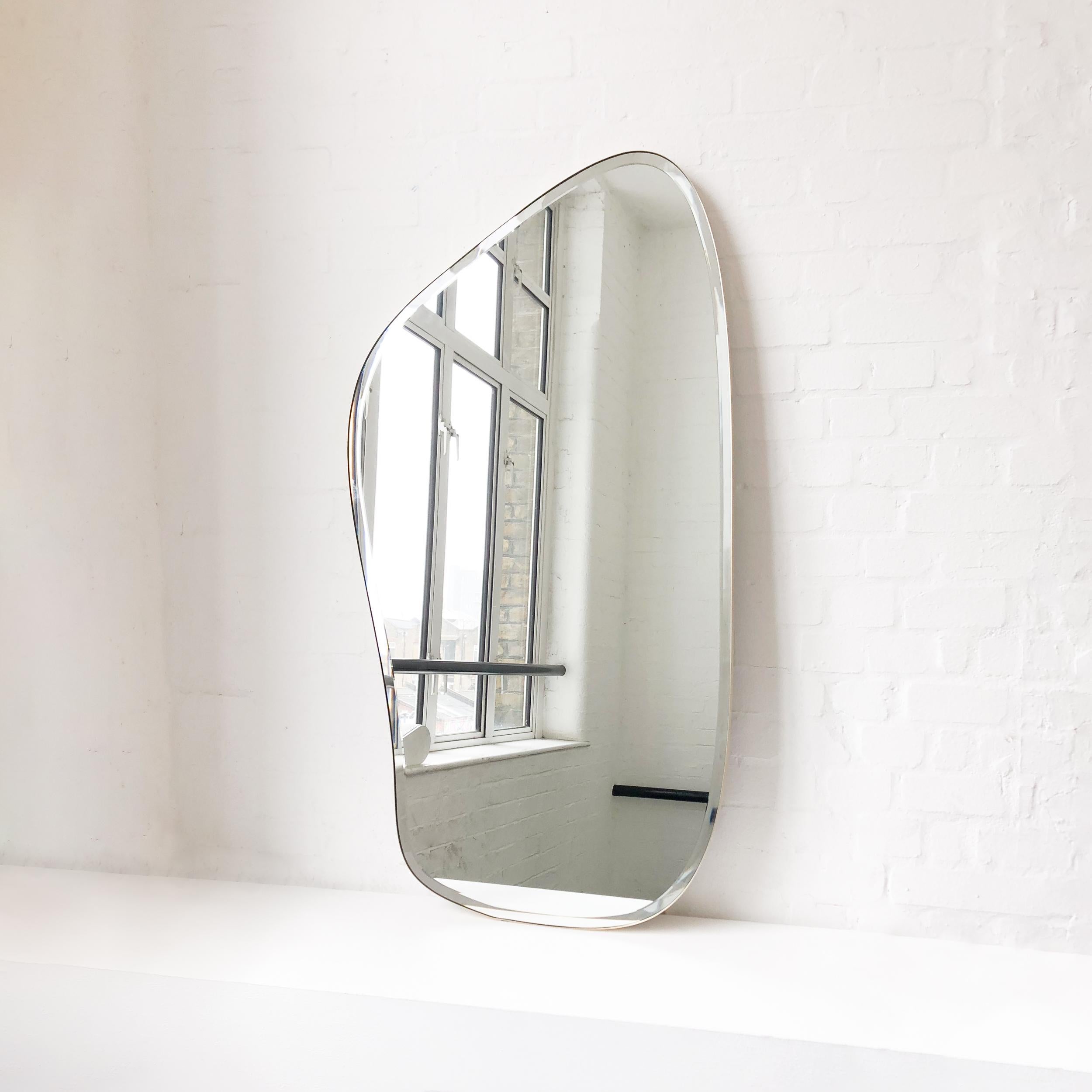 Modern freeform organic shaped wall mirror with a bevel, minimalist brass frame. Designed and handcrafted in London, UK. This mirror is fully customisable.

Dimensions: H 131.3cm x W 71.2cm x D 2.4cm / H 51.7in x W 28in x D 0.94in

Fitted with an