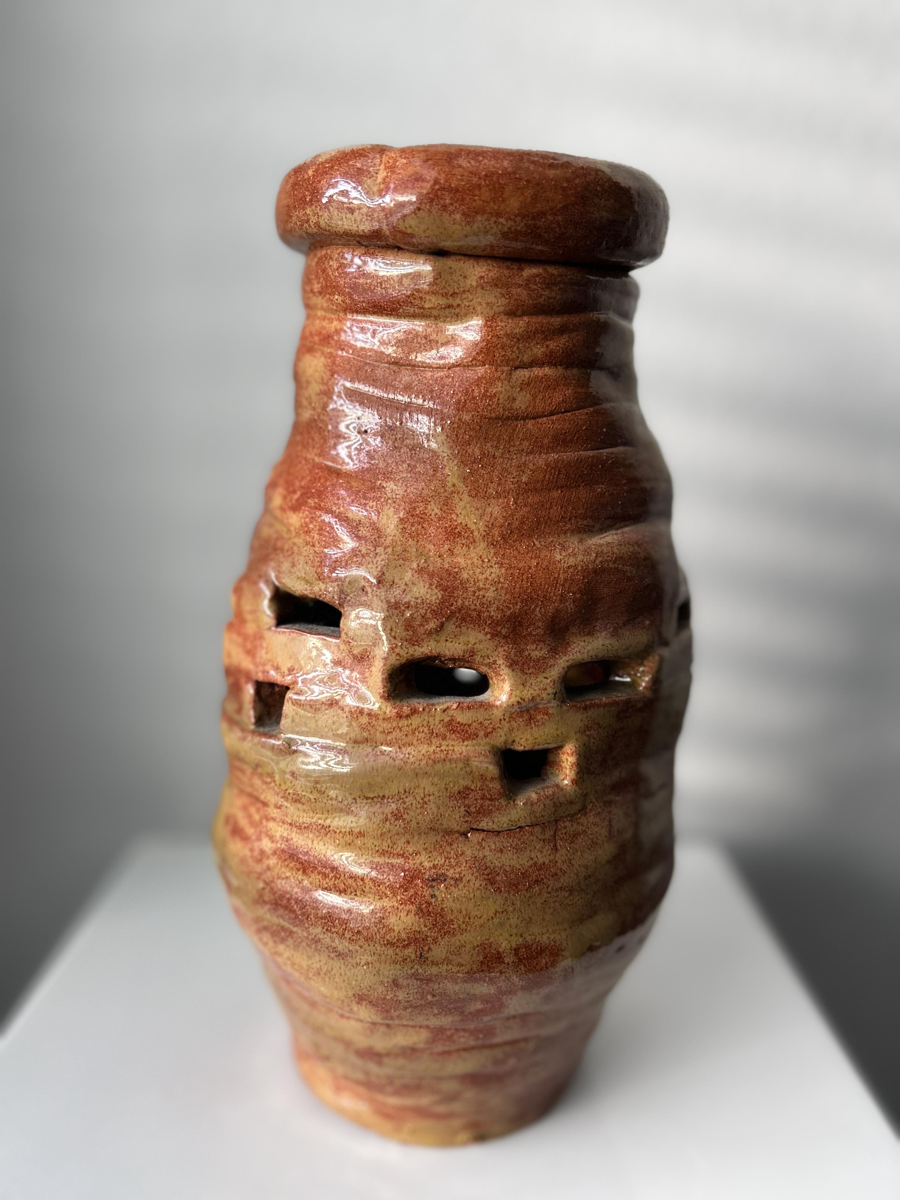 A red wood-fire stoneware vase . Hand-made, vase is shaped in a free form manner with perforated design. 

Artist signed.