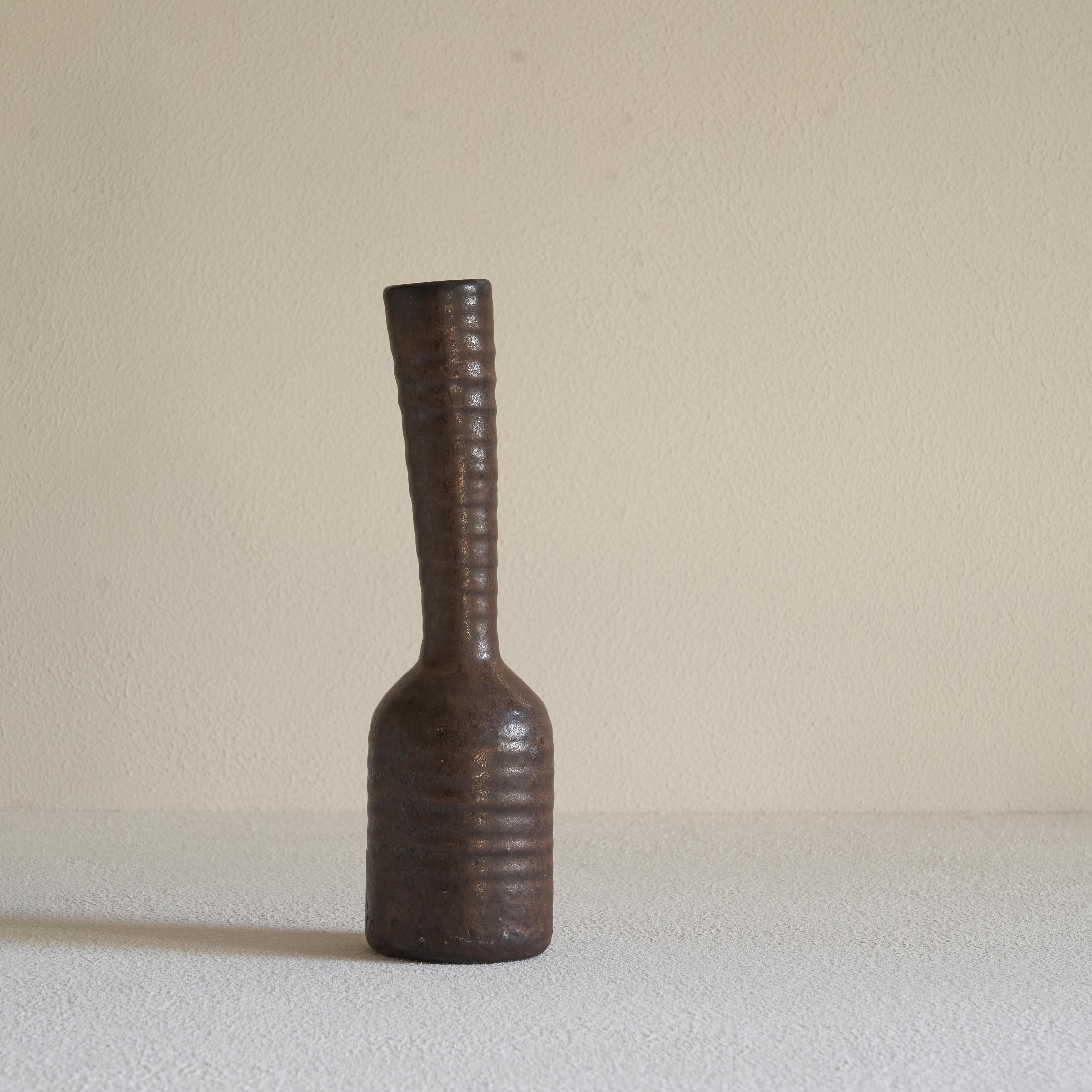 Freeform studio pottery vase 1960s.

This is a very distinct midcentury Studio Pottery vase with a slender freeform aesthetic. The dark brown vase has a rough and ribbed glaze and has a wonderful natural and wabi sabi appearance. The slender and