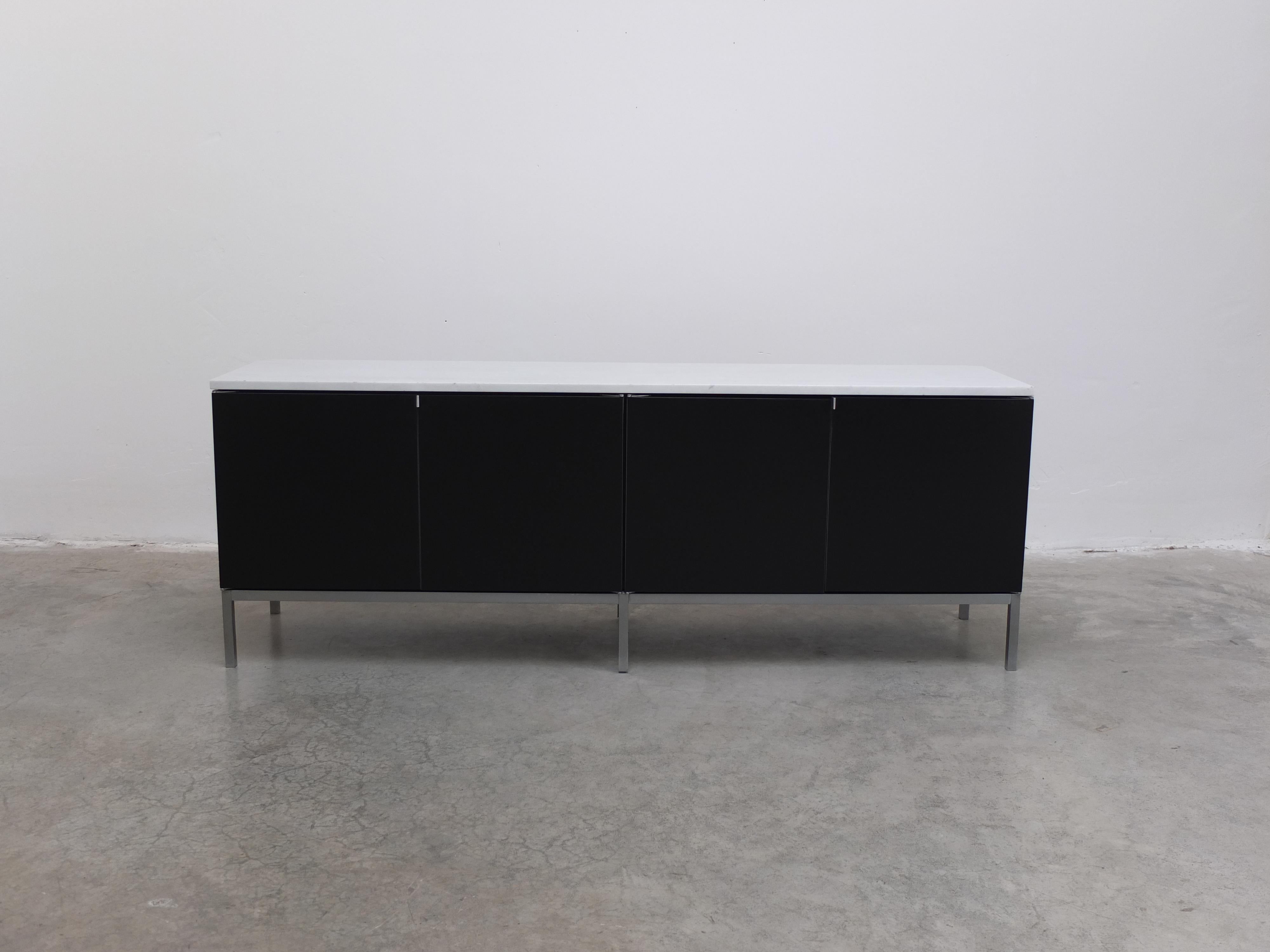 Superbe buffet haut de gamme conçu par Florence Knoll Basset en 1961. Cet exemplaire est en bois laqué noir avec quatre portes et des poignées en métal. À l'intérieur, on trouve les étagères en verre d'origine. Le plateau en marbre blanc ajoute une