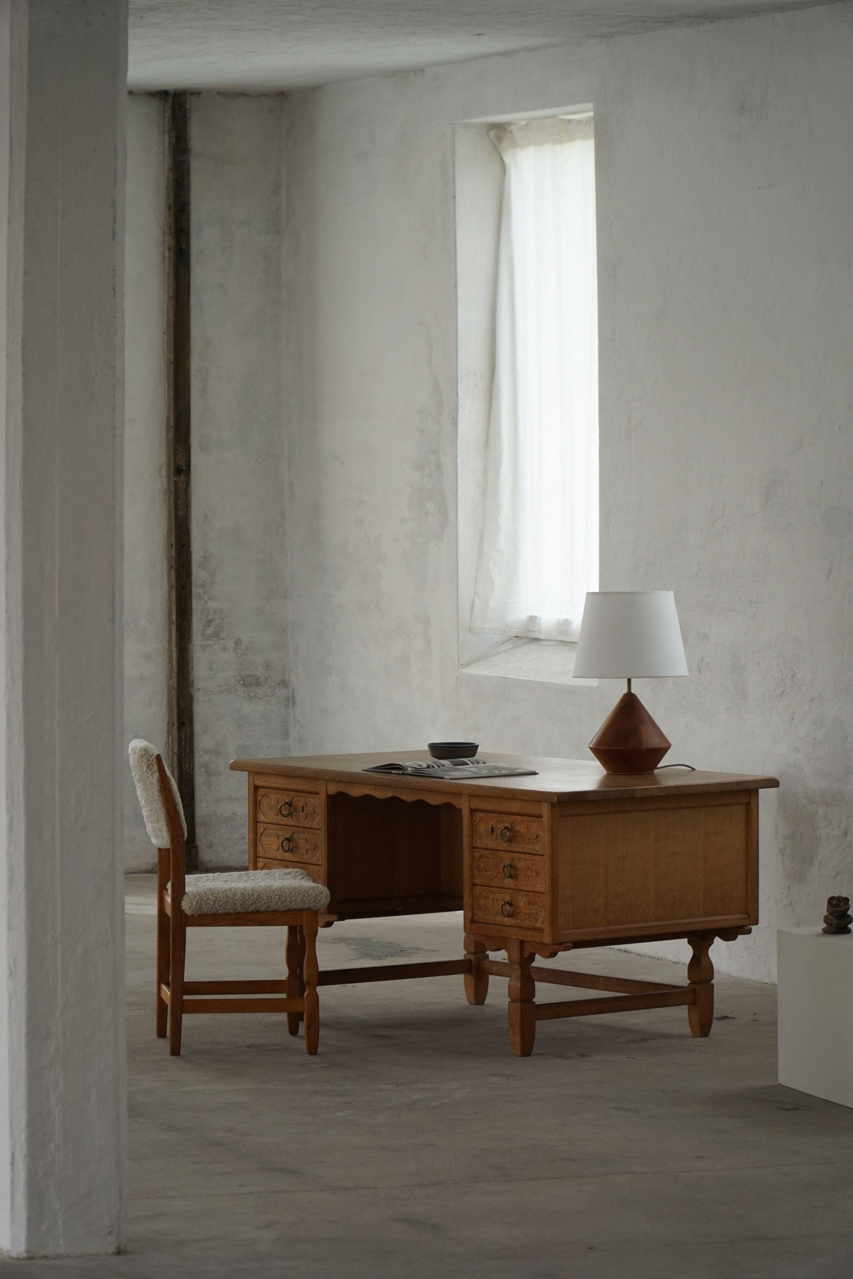 An elegant freestanding writing desk designed by Danish designer Henning Kjærnulf in the 1950s. Crafted in rich oak, the piece showcases a tactile warmth through its finely grained surface and clean, streamlined aesthetic.

The desk features a