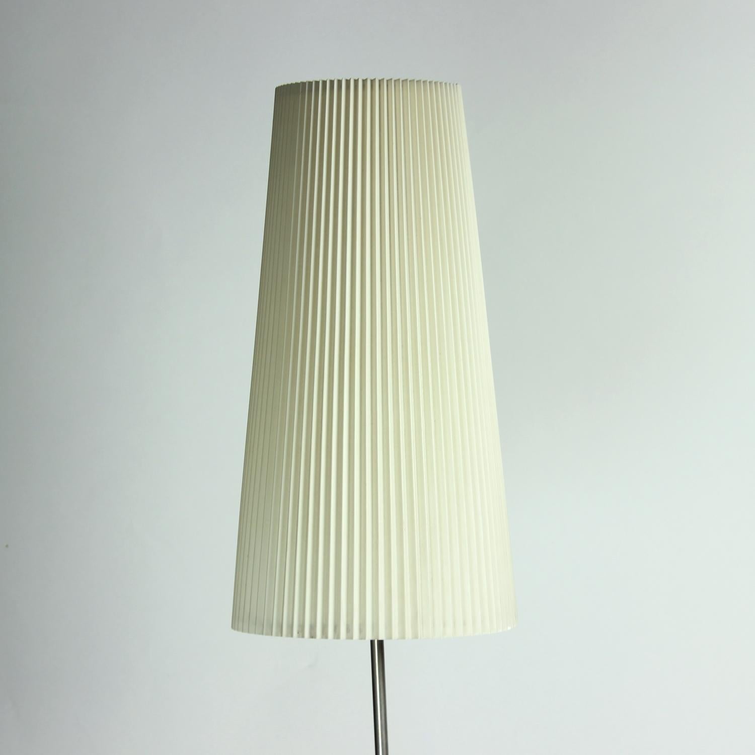 Elegant lampadaire sur pied de VEB Wohnraumleuchten en Allemagne. Produit dans les années 1970 à Berlin. La lampe porte encore l'étiquette d'origine sur le fond. La base est en métal noir. La tige centrale est en acier inoxydable et tient un élégant