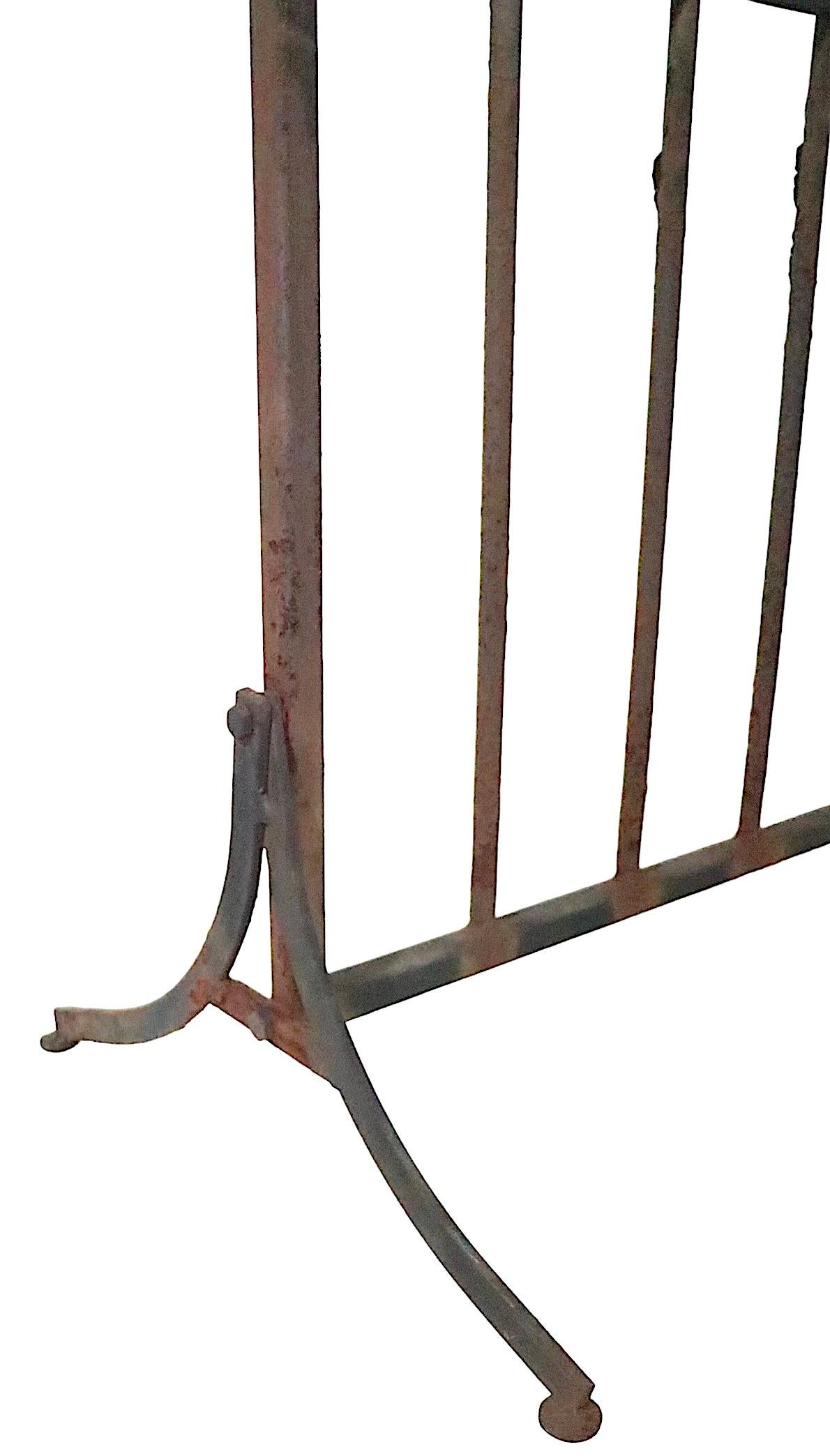 Unusual freestanding wrought iron plant stand having a bench like back with five ring form pot holders, which fit into the horizontal rails, as shown. The pot holders are movable and can be positioned to suit your needs and taste. The five rings