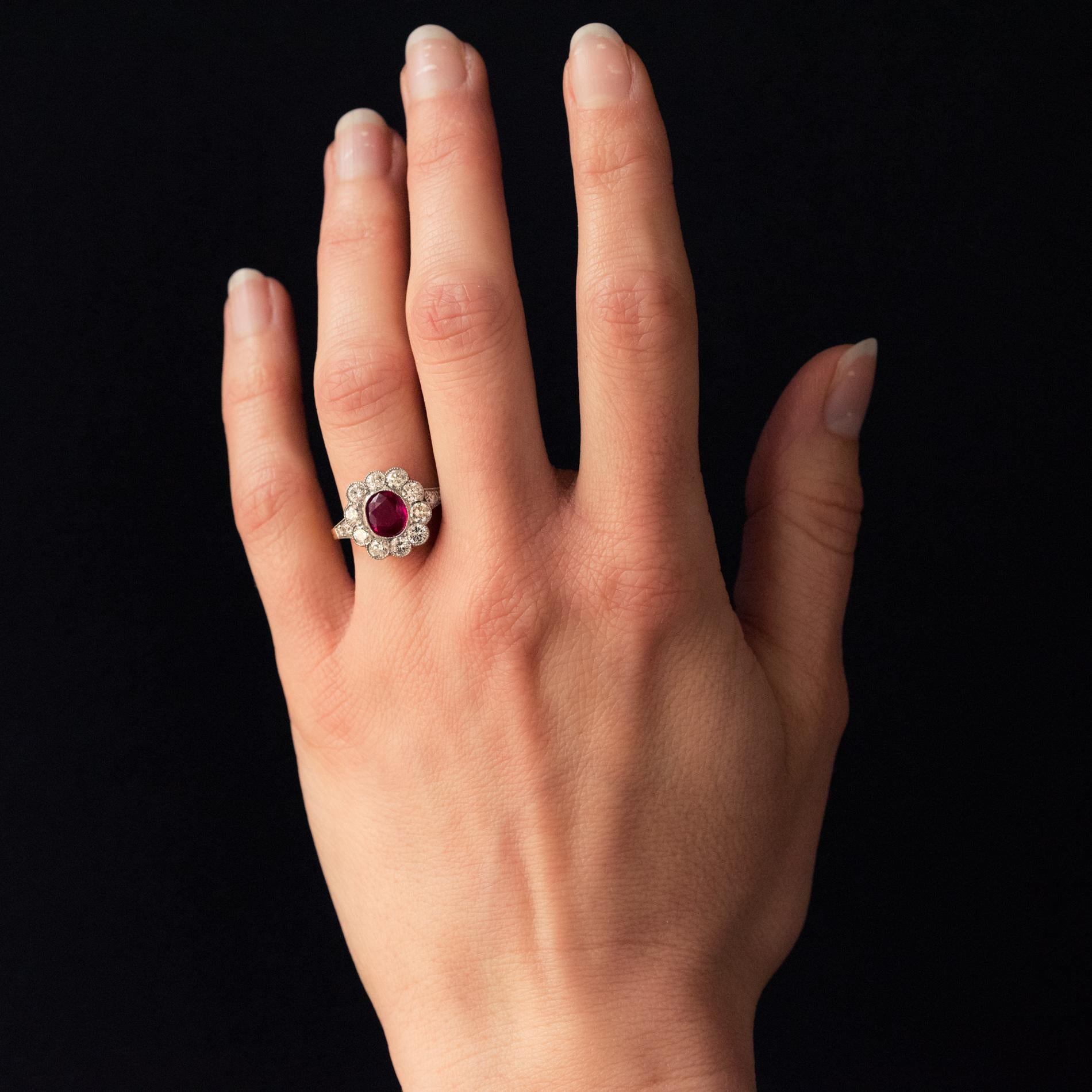 Ring in 18 karat yellow gold, eagle's head hallmark and platinum.
In the shape of a flower, this ring called a daisy is adorned with an oval ruby surrounded by modern brilliant-cut diamonds, all in millegrain settings. On both sides, 2 x 2