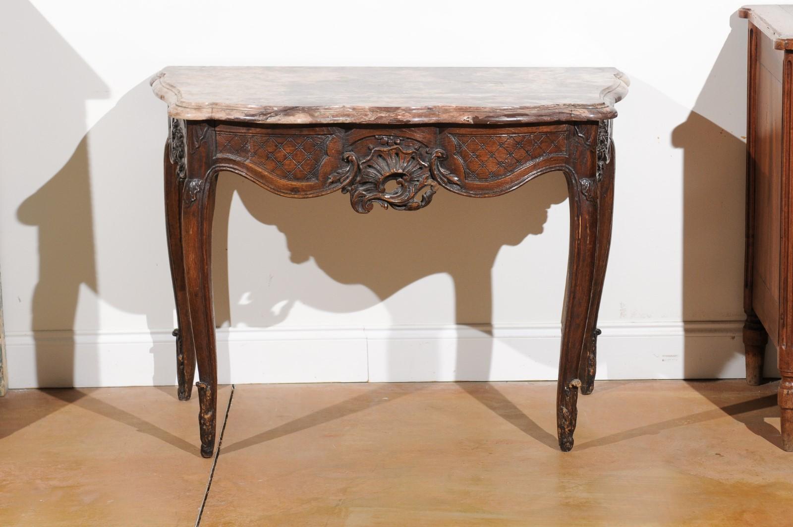 A French Régence period walnut console table from the early 18th century, with its original marble top. Born in France during the Régence period that saw the transition of power between the late Louis XIV and his great-grandson Louis XV who was