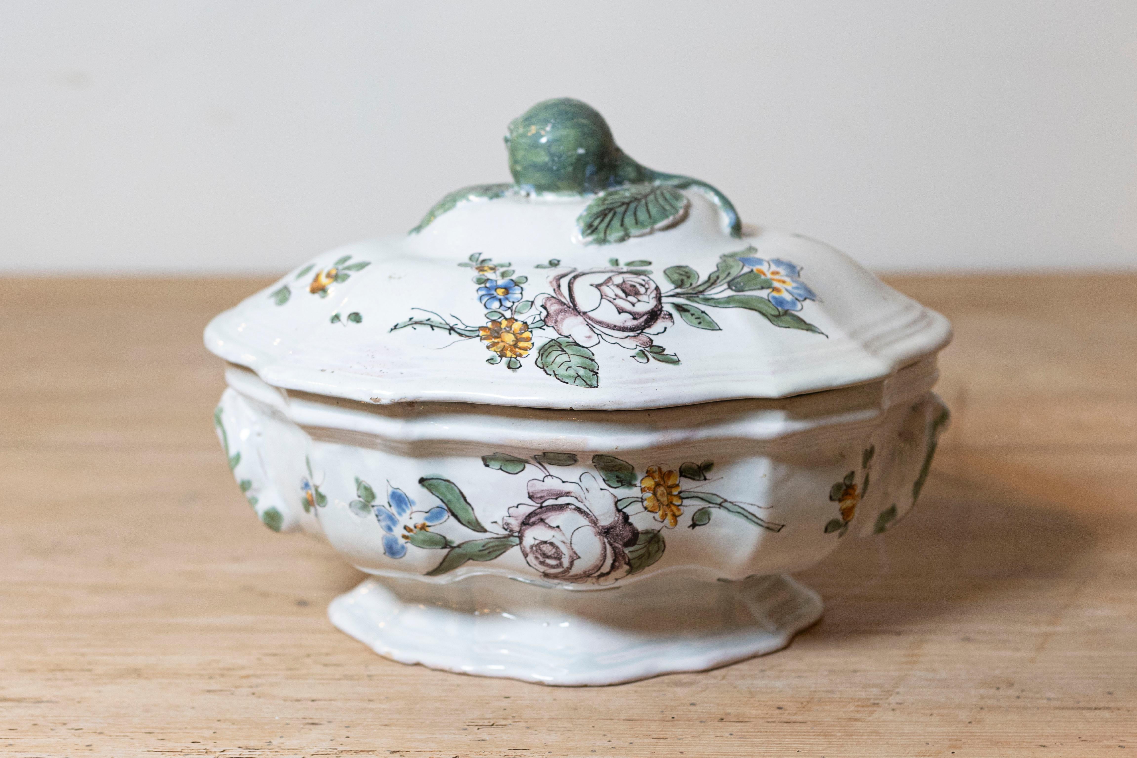 Sopera francesa faïence de mediados del siglo XVIII, de forma ovalada, procedente de Burdeos, con decoración floral. Creada en el suroeste de Francia durante el reinado de Luis XV, esta sopera presenta una forma ovalada perfectamente complementada