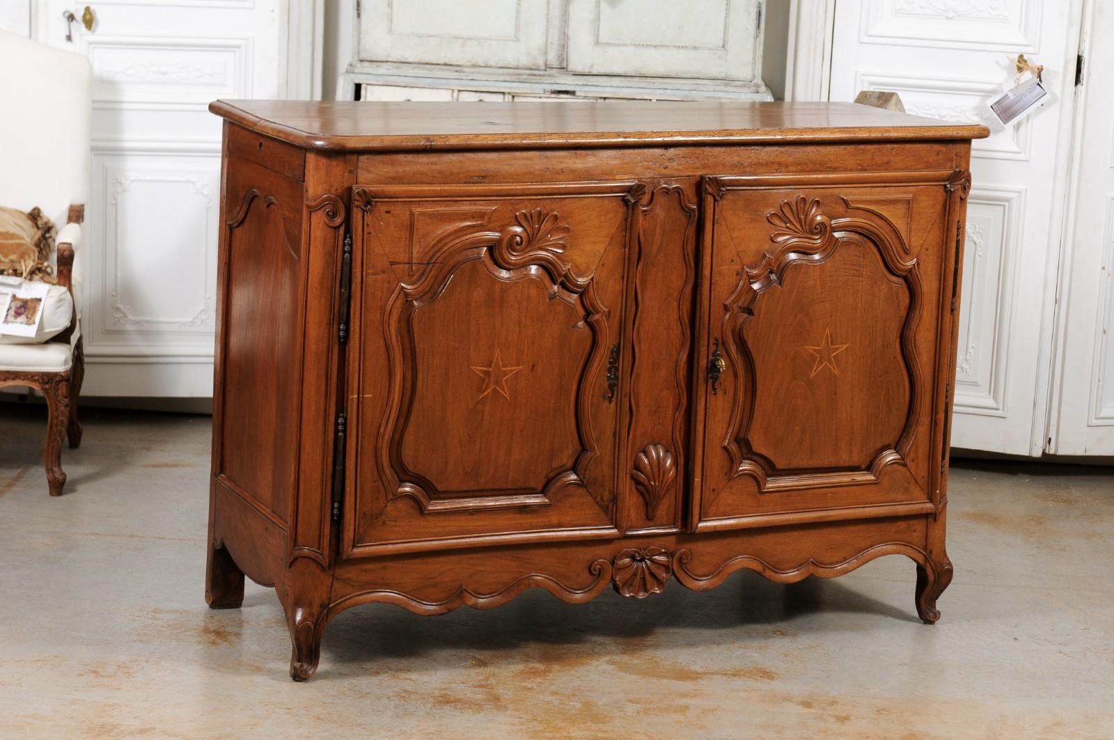 A French Louis XV period walnut buffet from the mid-18th century, with star inlay and carved shells. Created in France during the reign of King Louis XV nicknamed Le Bien-Aimé (the Beloved), this walnut buffet features a rectangular planked top with
