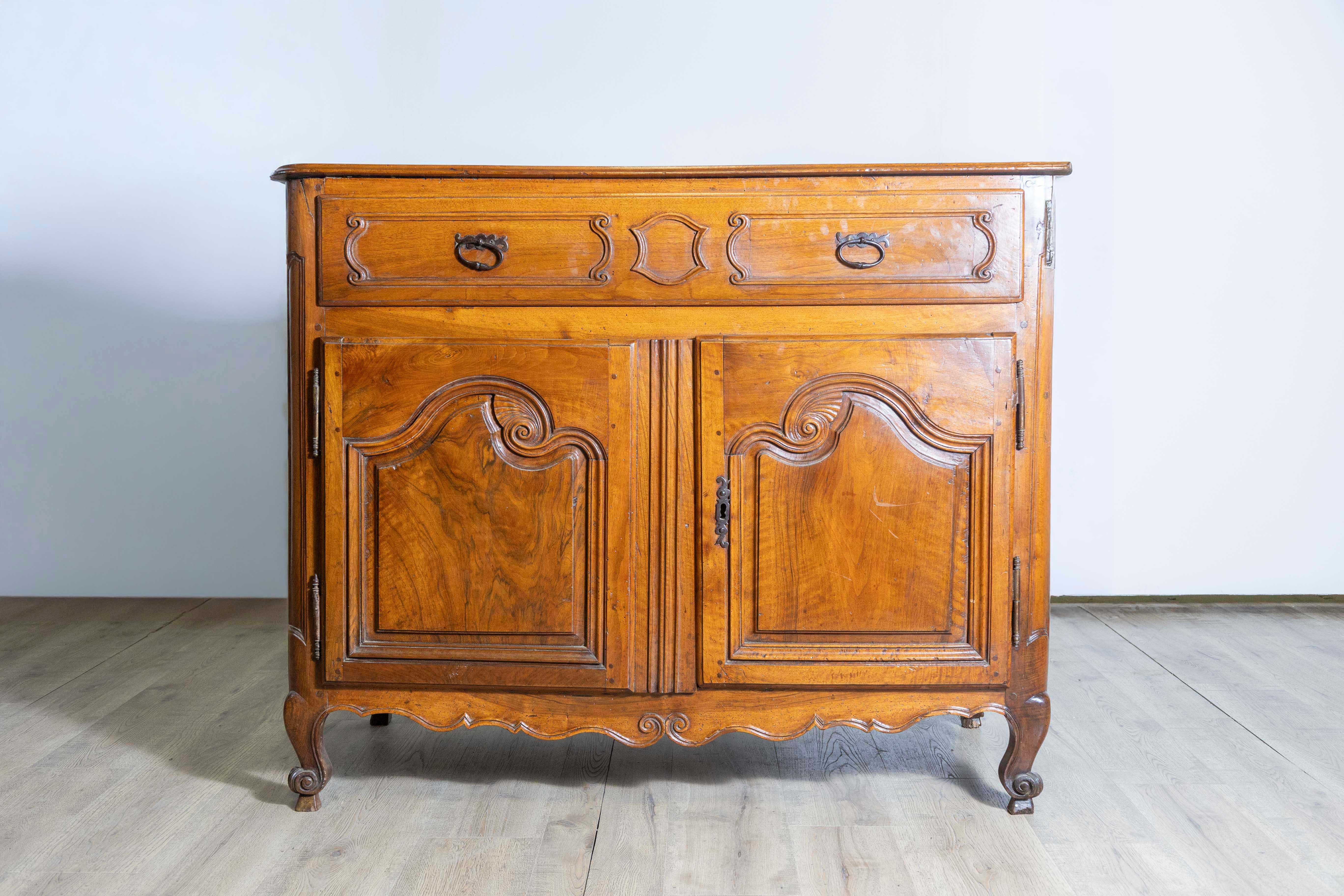Un buffet francese in noce del periodo Luigi XV della metà del XVIII secolo, proveniente dalla Provenza, con un cassetto singolo e due ante. Creato in Provenza durante il regno del re Luigi XV, soprannominato l'Amato (le Bien-Aimé), questo buffet in