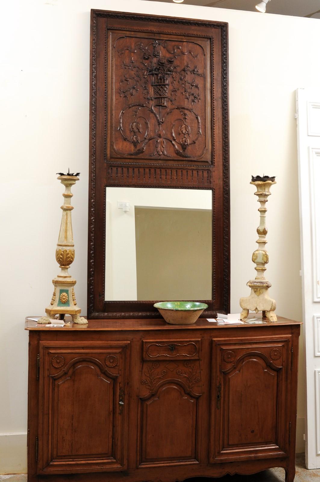 A French oak trumeau mirror from the mid-18th century with carved rinceaux and floral bouquet. Created in France during the 1750s, this oak trumeau mirror attracts our attention with its two large rinceaux from which are hanging grapes. From their