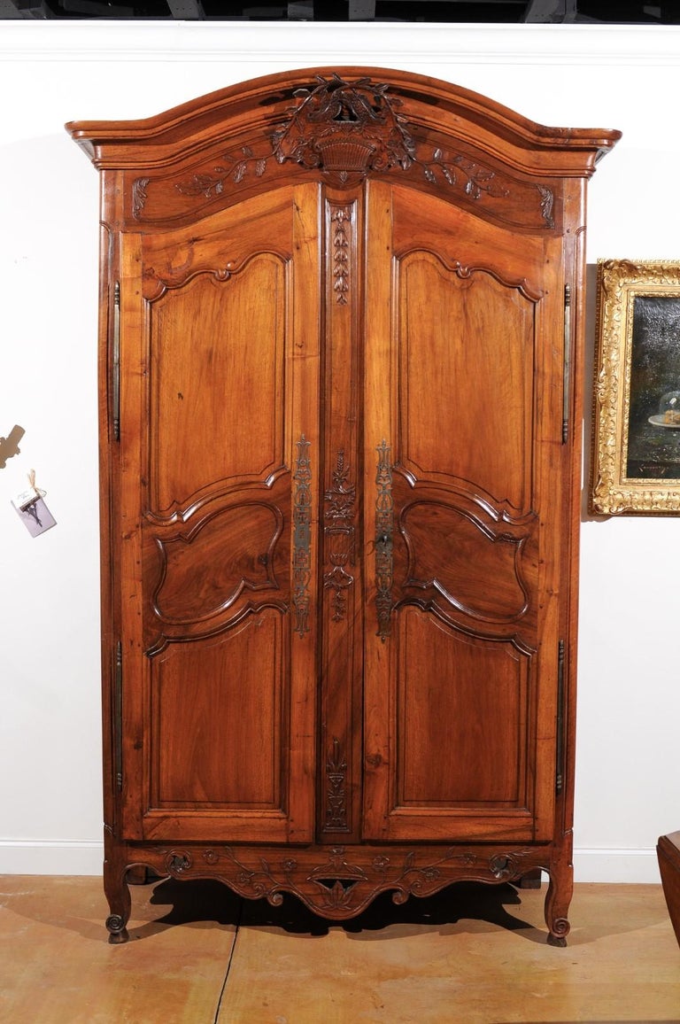 A French Louis XV period cherry Provençale chapeau de gendarme armoire from the late 19th century, with basket and kissing doves. Born in Provence at the end of King Louis XV's reign, this stunning cherry armoire features a 'chapeau de gendarme'