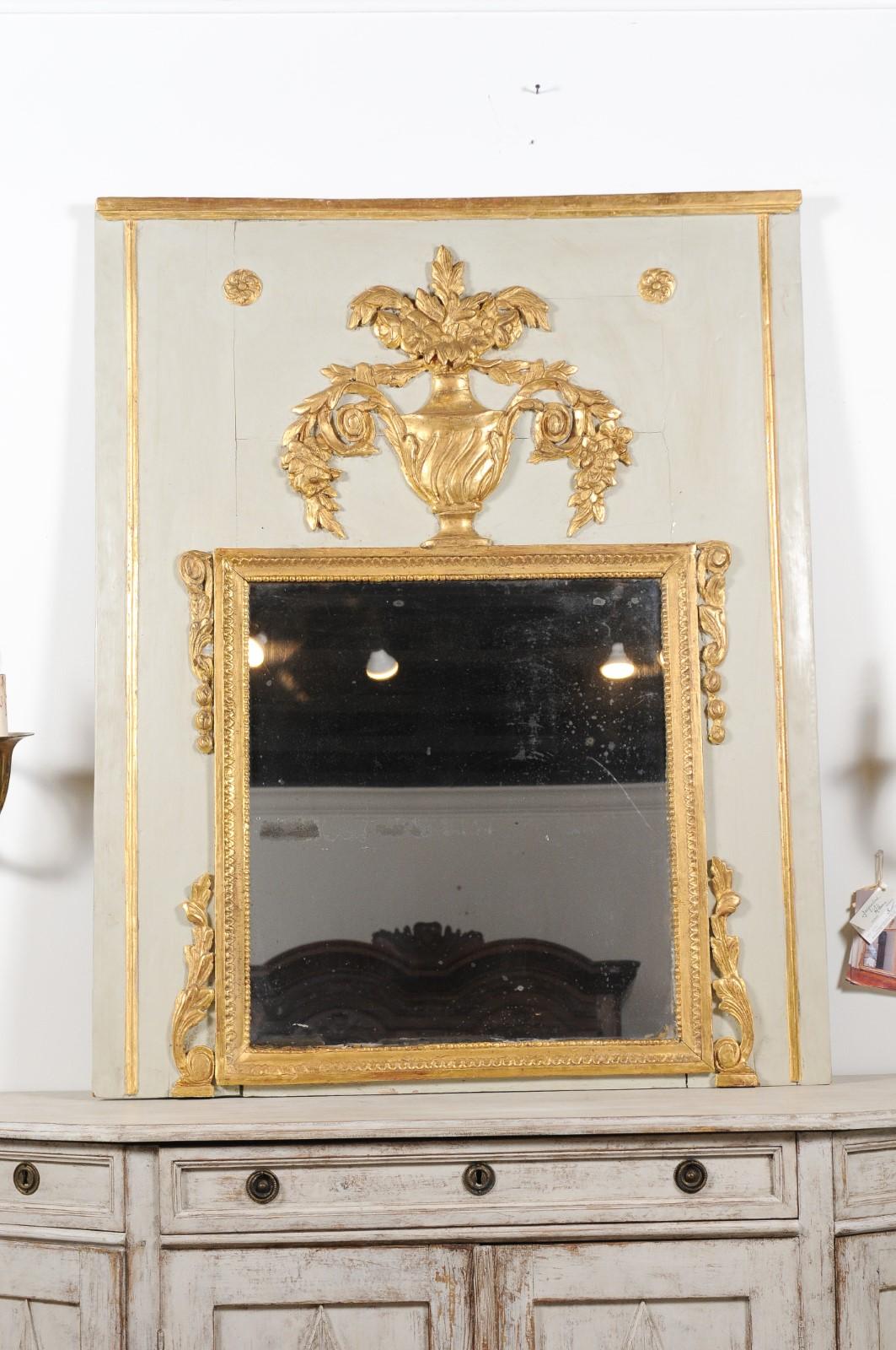 A French Transition period painted and gilt trumeau mirror from the 18th century, with urn, flowers, foliage and volutes. Created in France during the third quarter of the 18th century, this trumeau mirror presents the stylistics characteristics of