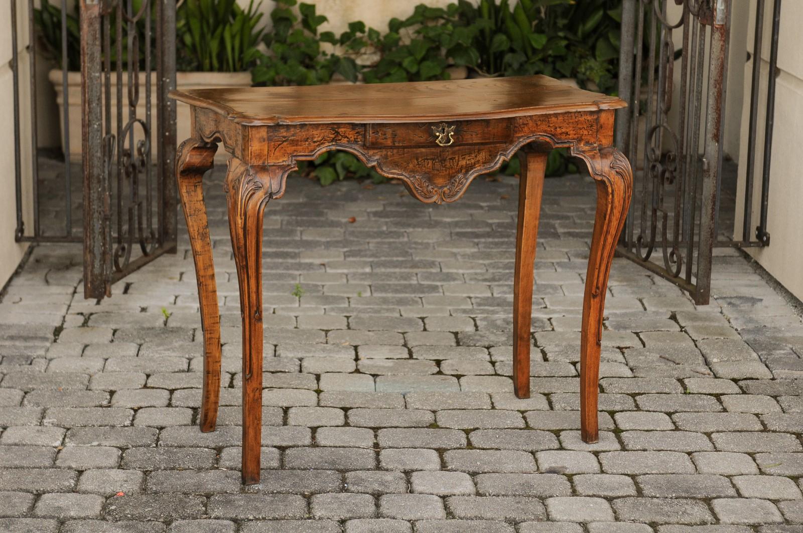 A French Louis XV style walnut and elm writing table from the late 18th century, with single drawer and cabriole legs. Born in France during the later years of the 18th century, this table features a rectangular planked top with beveled edges and