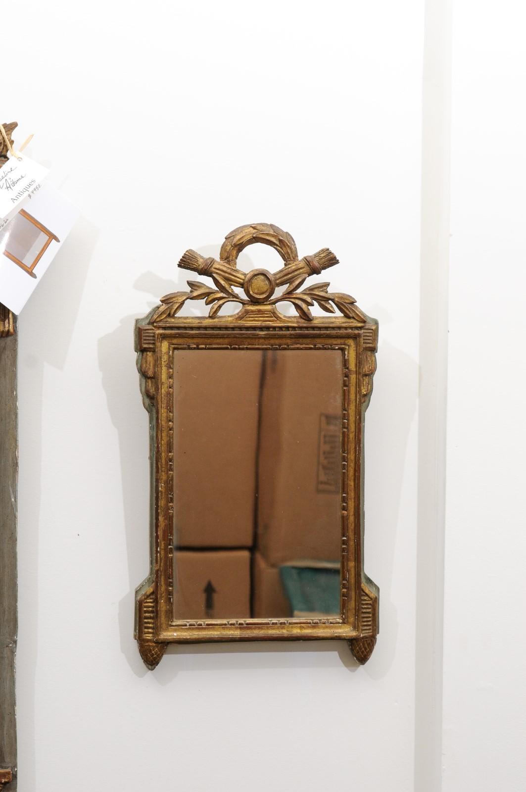 A French Louis XVI period gilt and painted mirror from the late 18th century, with carved crest. Created in France during the last decade of the 18th century, this gilt mirror attracts our attention with its crest carved with quivers and arrows