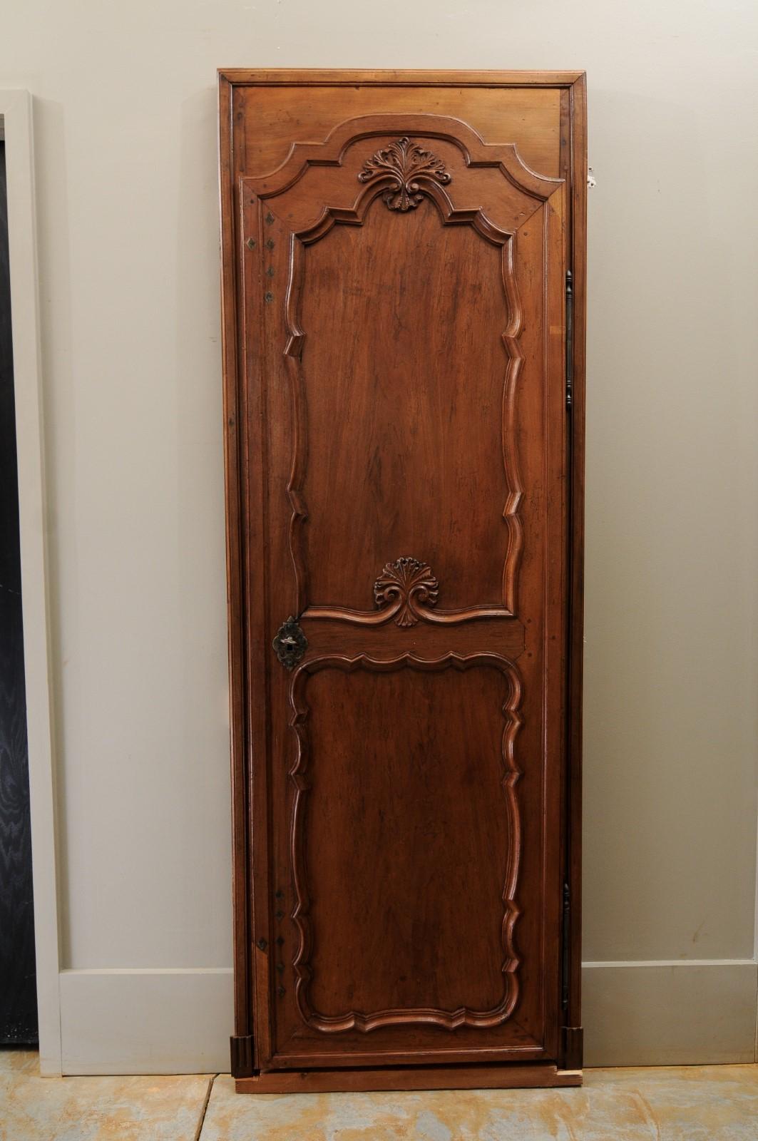 A French Louis XVI period wooden communication door from the late 18th century, with carved foliage motifs. Created in France during the last decade of the 18th century, this French door features two molded panels topped with a skillfully carved