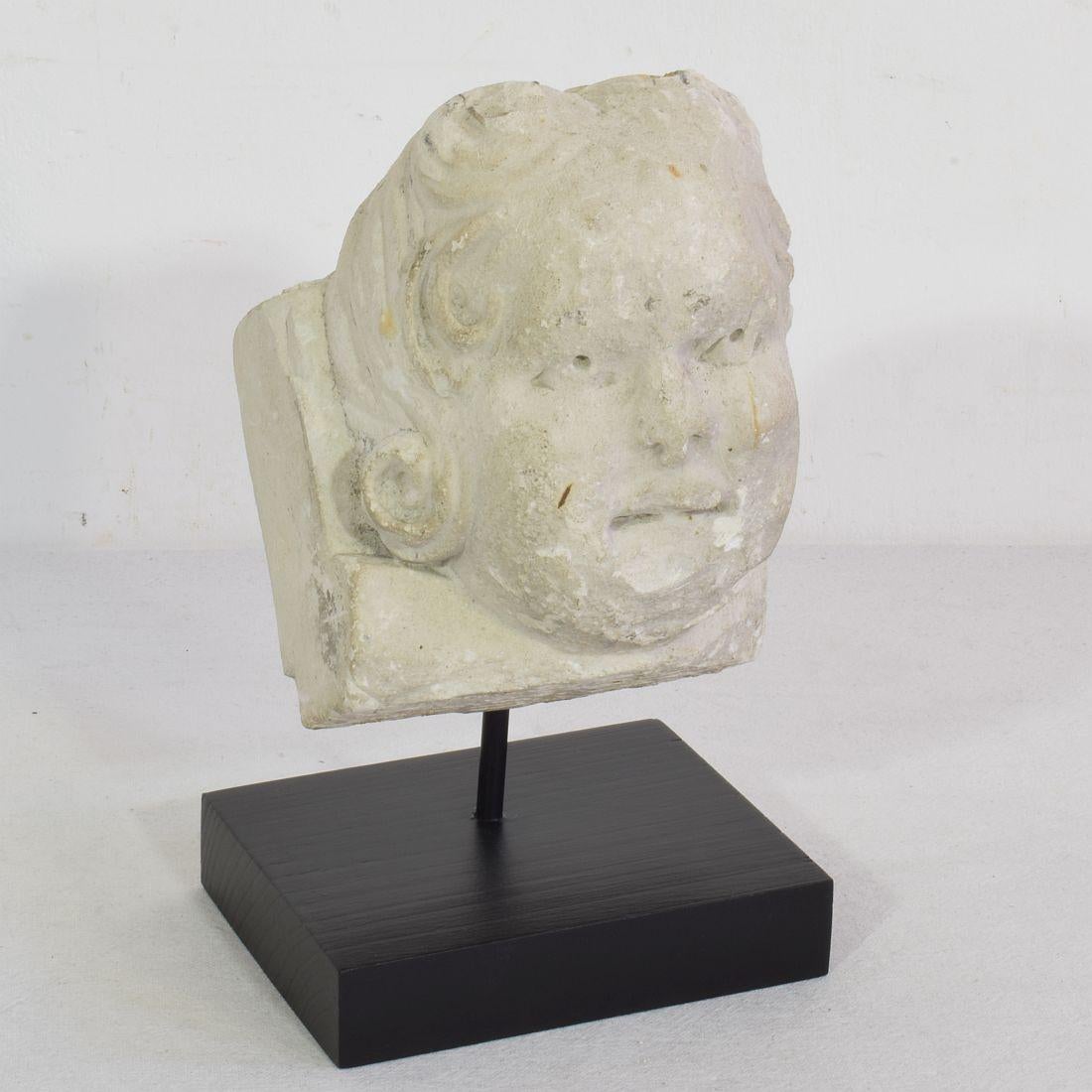 Magnifique tête d'ange en pierre sculptée à la main et usée par les intempéries, qui ornait autrefois une façade.
France, vers 1650-1750.
Météorisé.
Les mesures comprennent la base en bois.