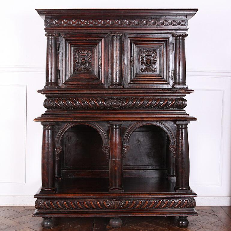 An ornately-carved walnut 17th century and later French cabinet on stand, the top with a pair of carved doors and paneled carved sides with columns at the corners, the whole raised on a base with columns and arches below a heavily-gadrooned apron