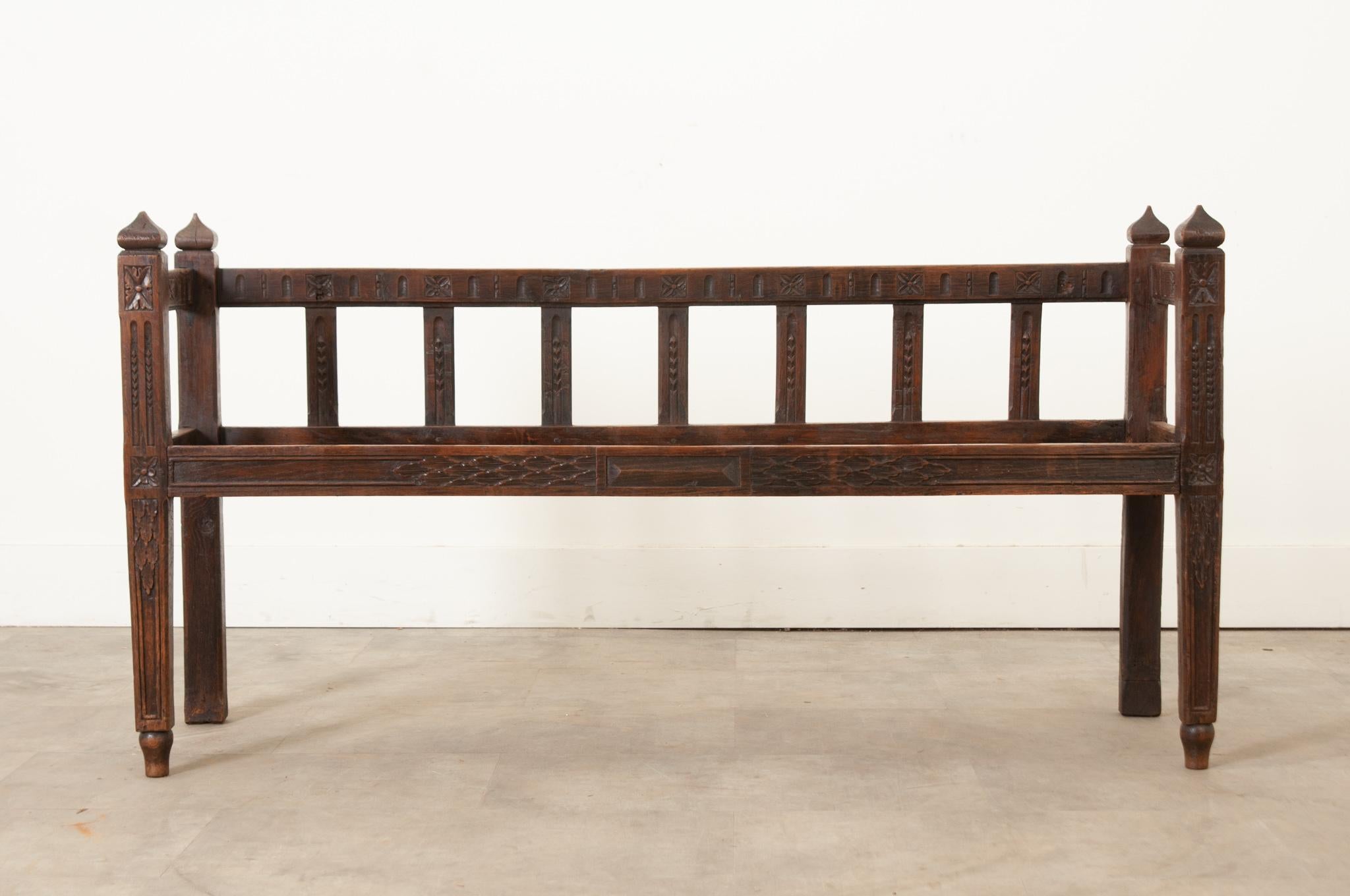 This unique and interesting solid oak bench is perfect for a hallway or smaller seating area. This bench has a scooped out seat, a custom cushion would have been made to fit perfectly. The bench has carvings throughout and has recently been cleaned