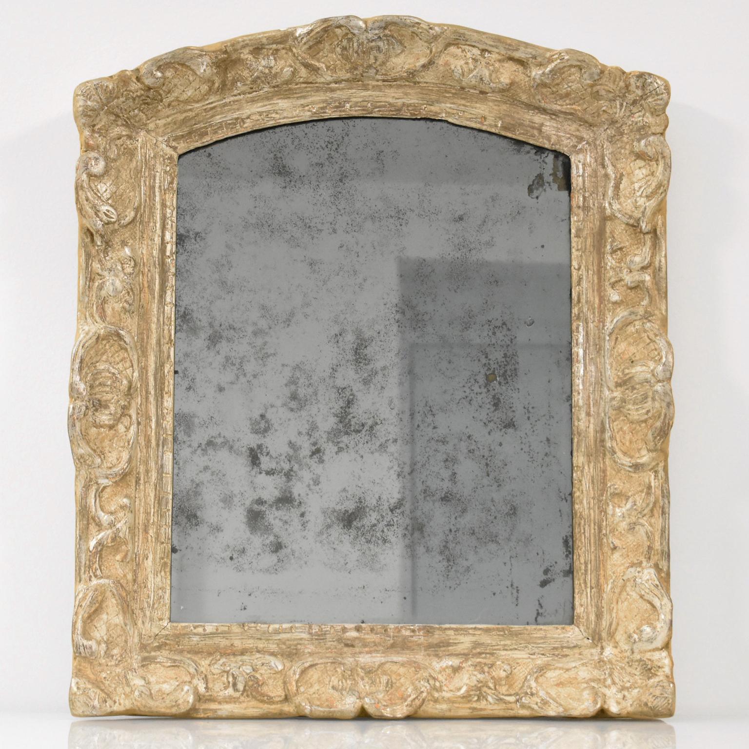 This museum-quality elegant hand-carved oak wall mirror was crafted in France in the 17th century. The piece boasts a high-quality Louis XIV period framing with silver leaf gilding in 