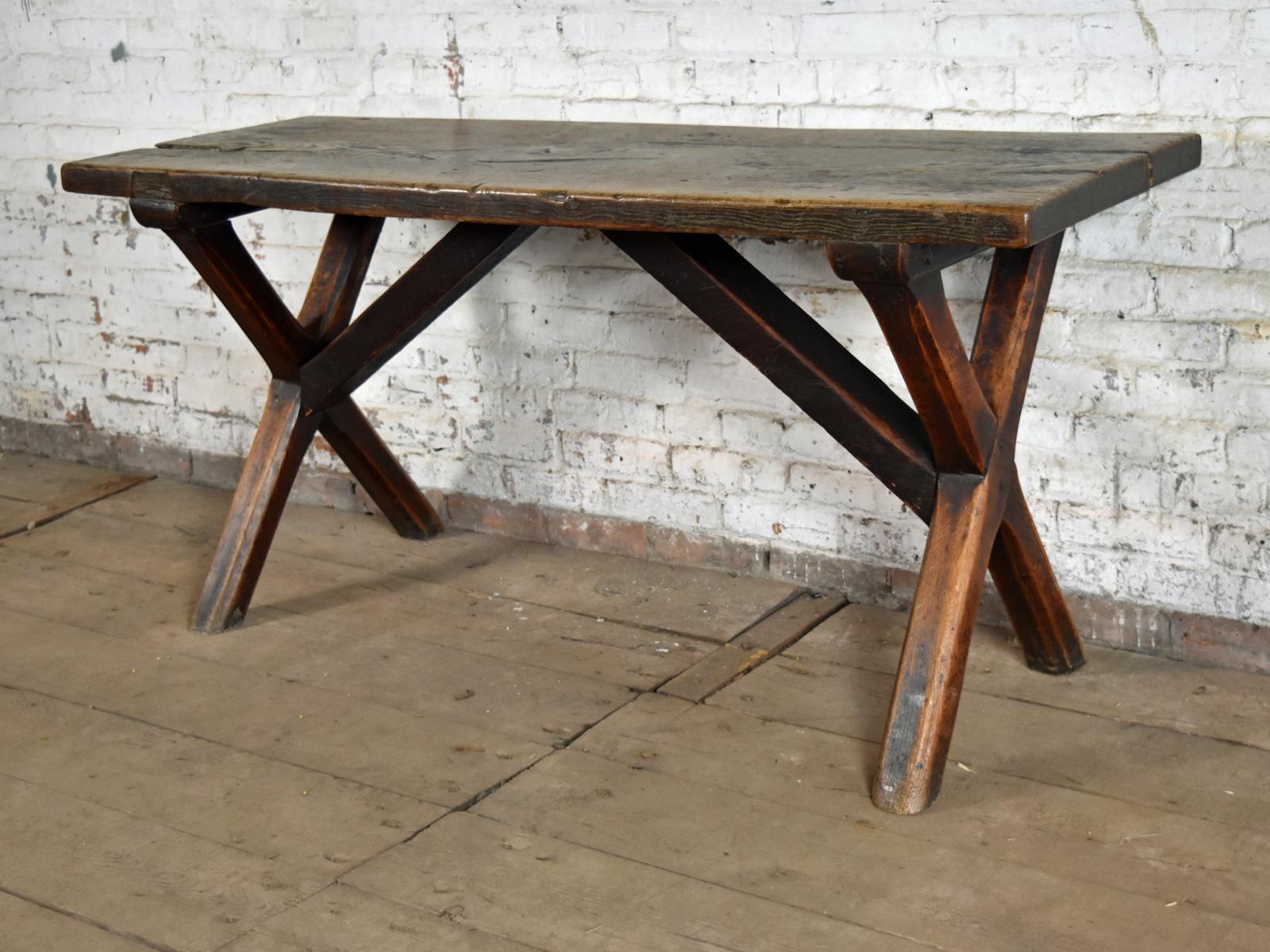 Unique, charming rustic console table of interesting, linear design, featuring an oak trestle base constructed of chamfered X-form legs and conforming middle supports for the thick elm top. 
The table has been left in 