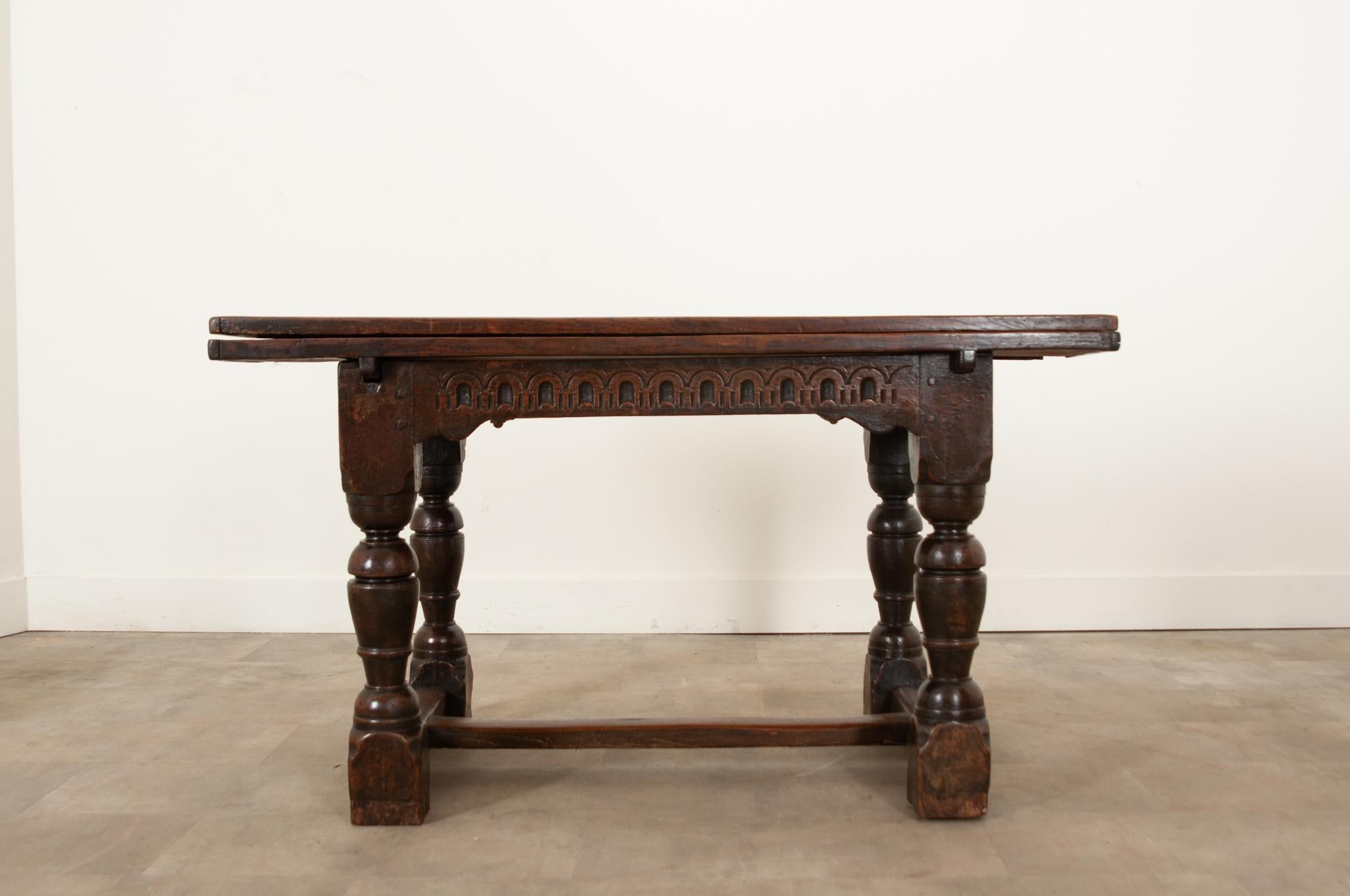 A robust, solid oak extending dining table hand-crafted in 17th century France circa 1680. Gnarled knots, beautiful grain, and an incredible range of textures give the thick tabletop its abundant character. The decorative hand-carved apron features