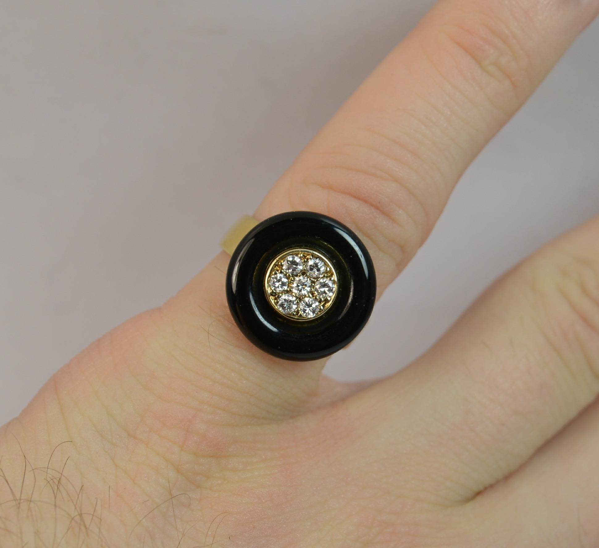 
A very stylish vintage cluster ring.

Solid 18 carat yellow gold example.

The central panel set with seven round brilliant cut diamonds to the centre with an onyx circular surround. VS diamonds.

15mm diameter to the head, 4.3mm thick band