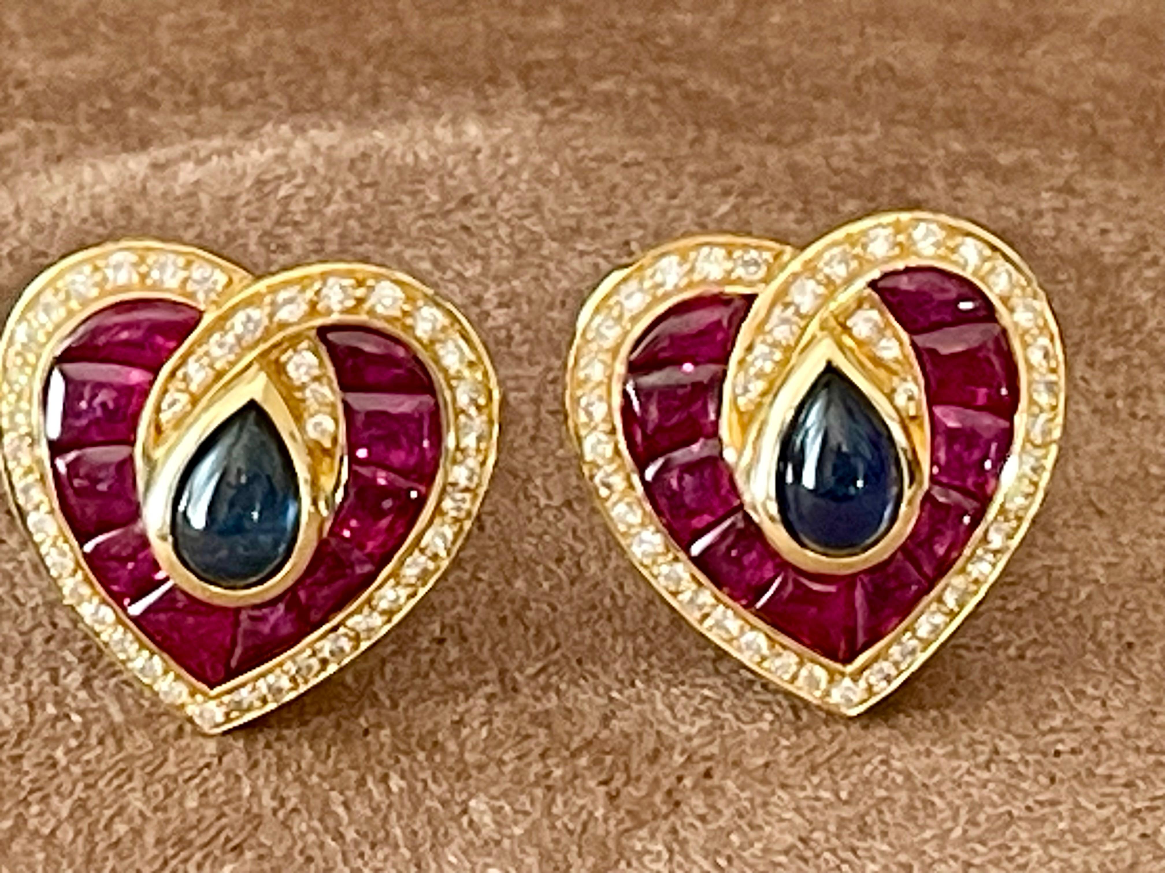 A pair of lovely 18 K yellow Gold heart shaped earclips of french provenance. These colorful earclips feature 2 lovely blue Sapphire Cabochons weighing 2.50 ct, 2o finely calibrated Rubies weighing 5.43 ct and Diamonds weighing 0.63 ct, G, color,