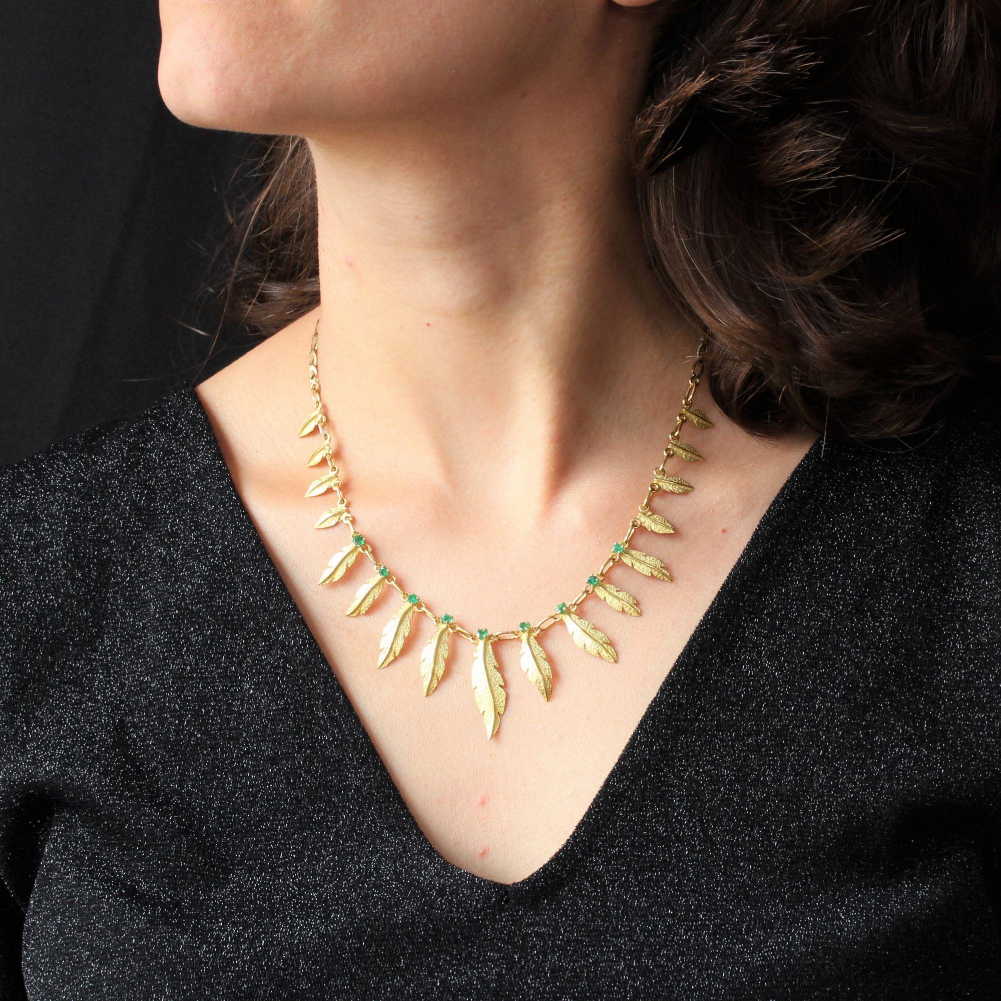 Necklace in 18 karat yellow gold, eagle head hallmark.
This very original retro necklace consists of a row of falling leaves, the nine largest of which are topped with an emerald. The rest of the retro jewelry ends in an oval folded mesh, up to the
