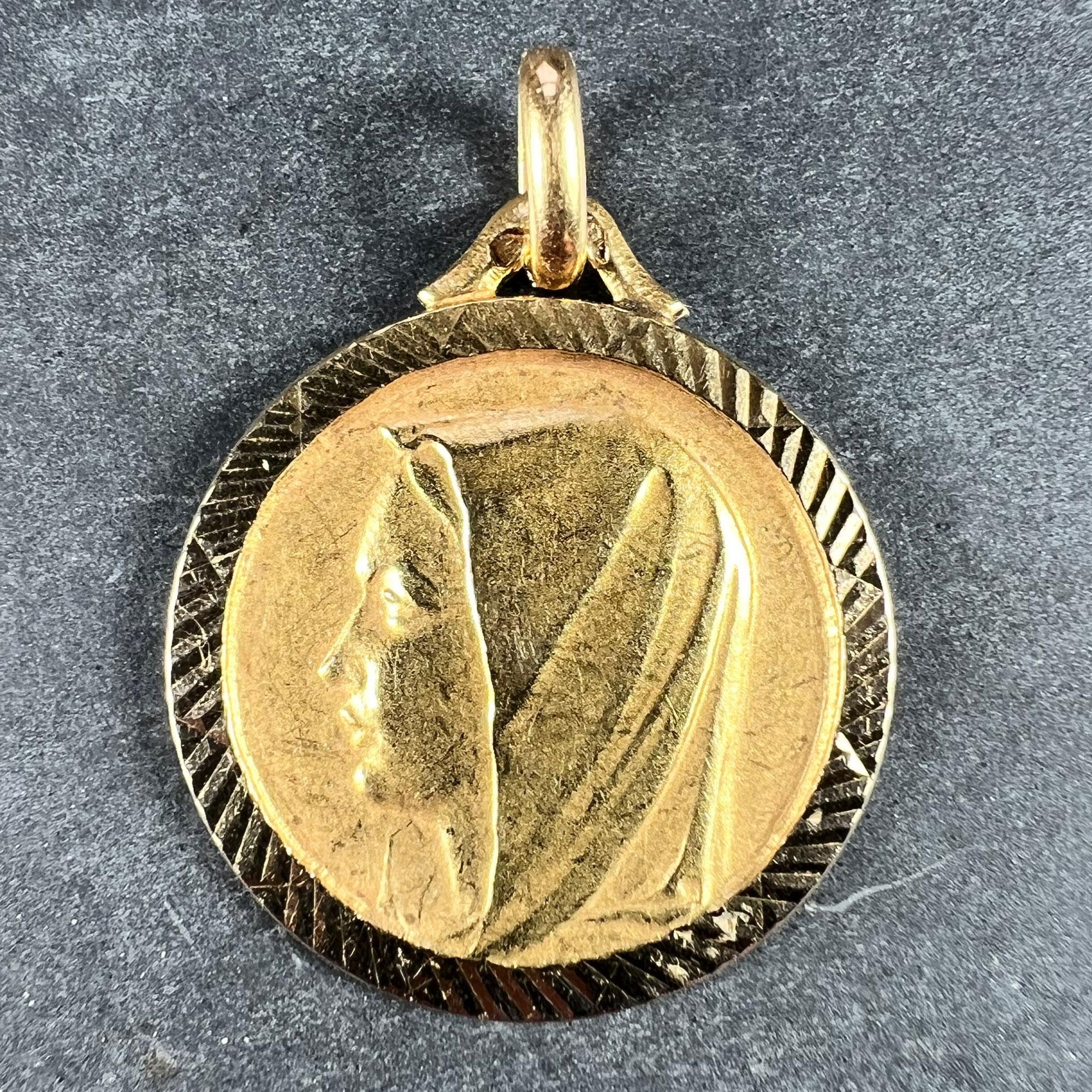 A French 18 karat (18K) yellow gold charm pendant designed as a medal depicting the Virgin Mary. Engraved to the reverse ‘Martine 27-3-57’. Stamped with the French eagle’s head for 18 karat gold and an unknown maker’s mark.

Dimensions: 2.5 x 2.1 x
