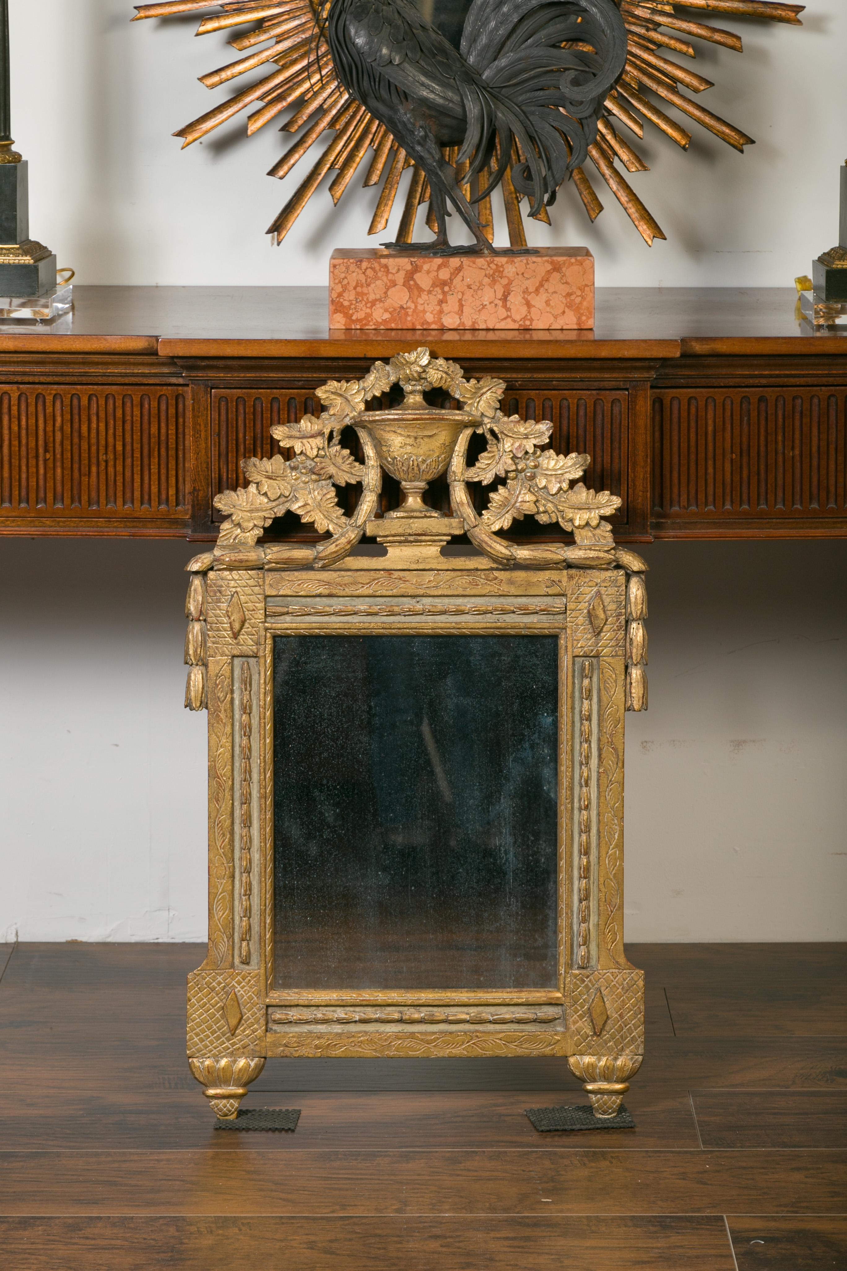 A French giltwood mirror from the early 19th century, with carved crest depicting urn, foliage and garlands. Created in France during the first decade of the 19th century, this giltwood mirror attracts immediately our attention with its carved crest