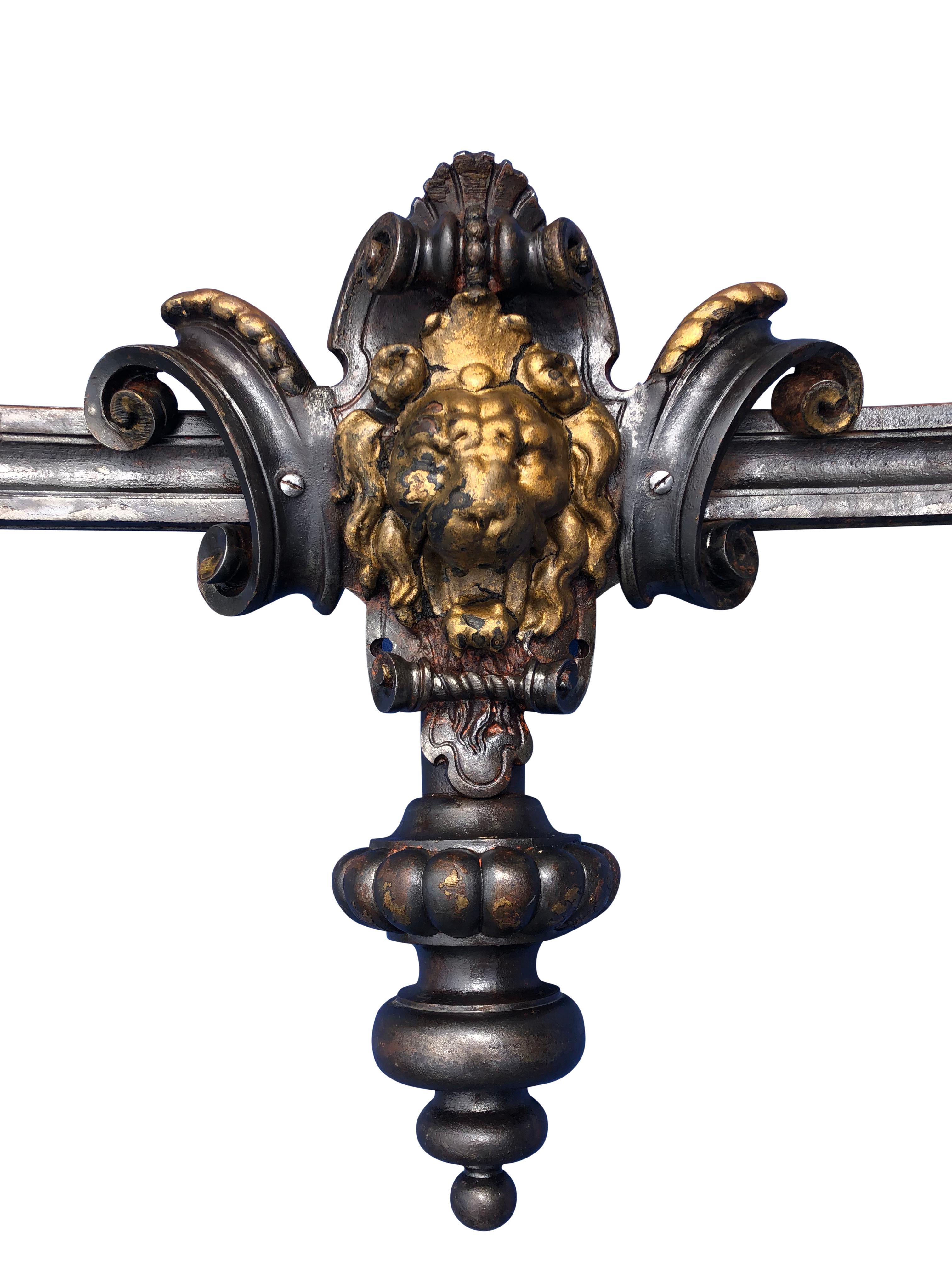 This is truly a one of a kind light. It is from late 19th century France and is made of solid forged iron with an intricately designed brass lion head and two attached decorative arms with brass cone tops and brass details that hold the lights. The