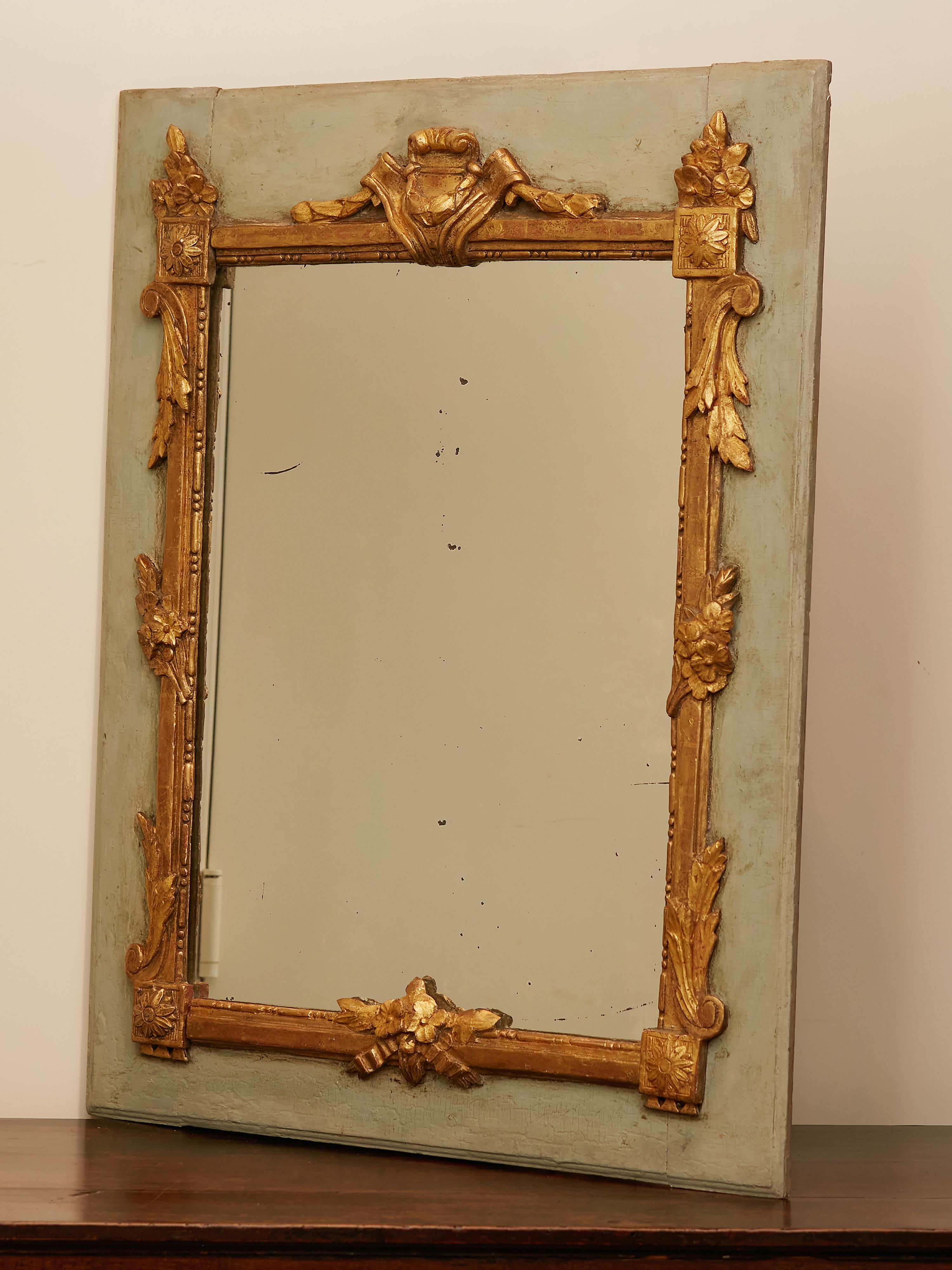 A French painted and carved giltwood mirror from the early 19th century, with cartouche, flowers and foliage motifs. Created in France during the early years of the 19th century, this rectangular mirror features a painted frame accented with