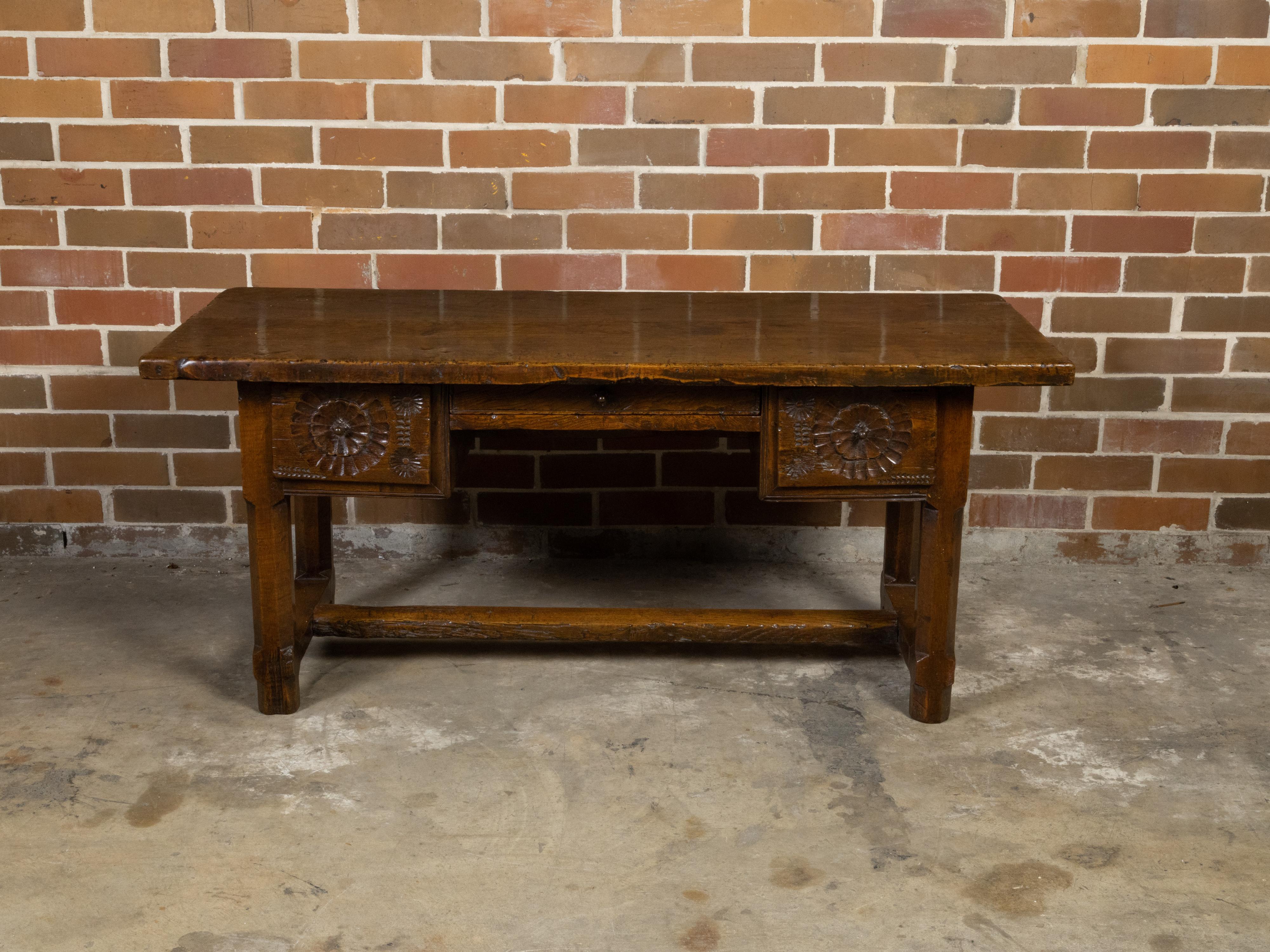 Scrivania in noce francese dell'inizio del XIX secolo con tre cassetti, motivi intagliati, stipite a croce H. H. e una bella patina. Creata in Francia nei primi anni del XIX secolo, questa scrivania in legno di noce presenta un piano rettangolare
